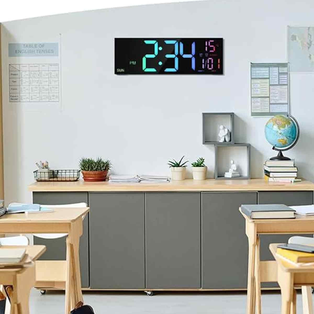 Digitaluhr zeigt 2:34 und 15:01. In einem Klassenzimmer mit Tischen und Dekoration.