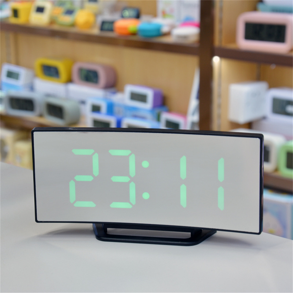 Schwarze Digitaluhr mit grüner Anzeige 23:11. Mehrere Uhren im Hintergrund.