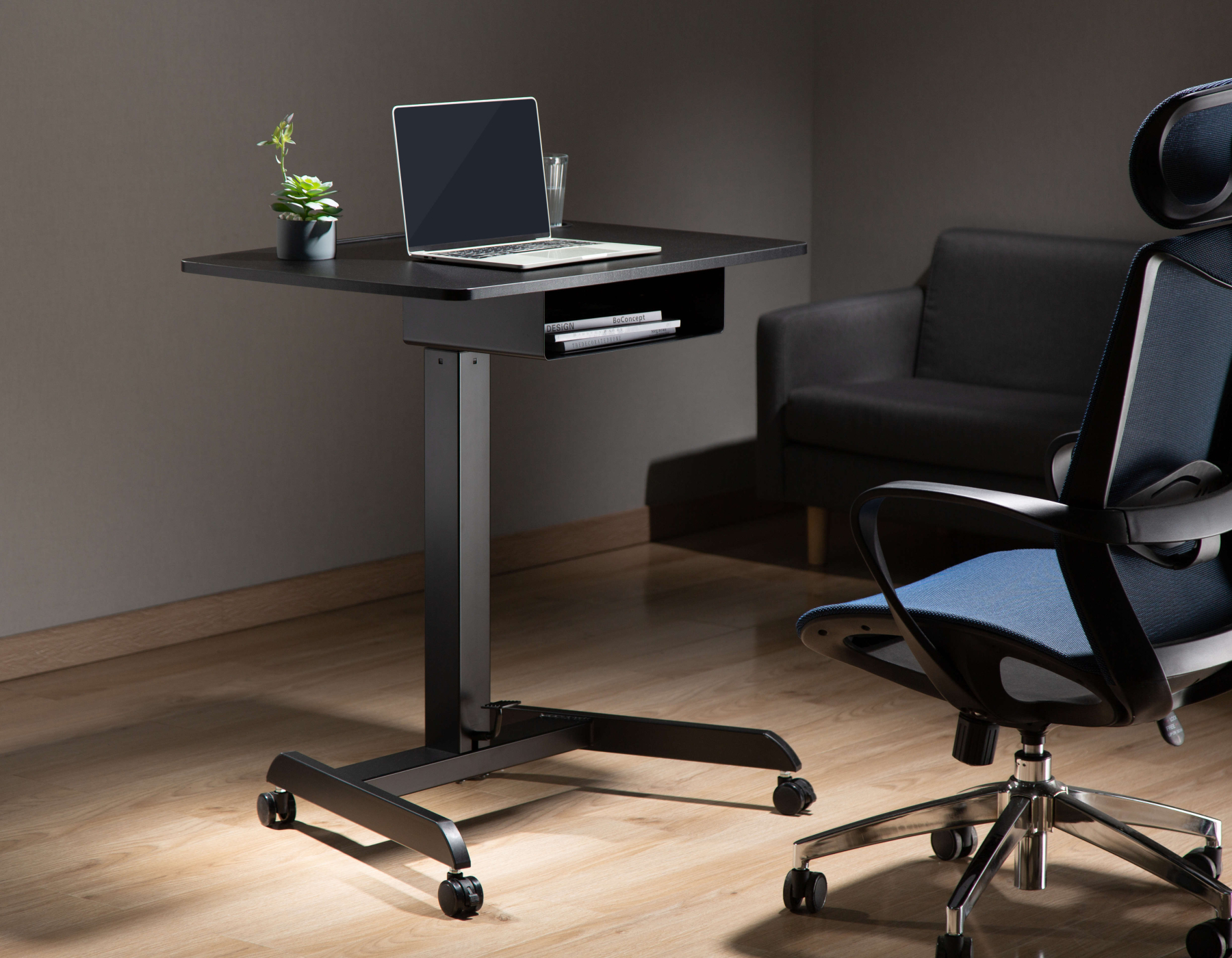 In hoogte verstelbaar bureau met een laptop en een stoel, in een moderne kantoorruimte.