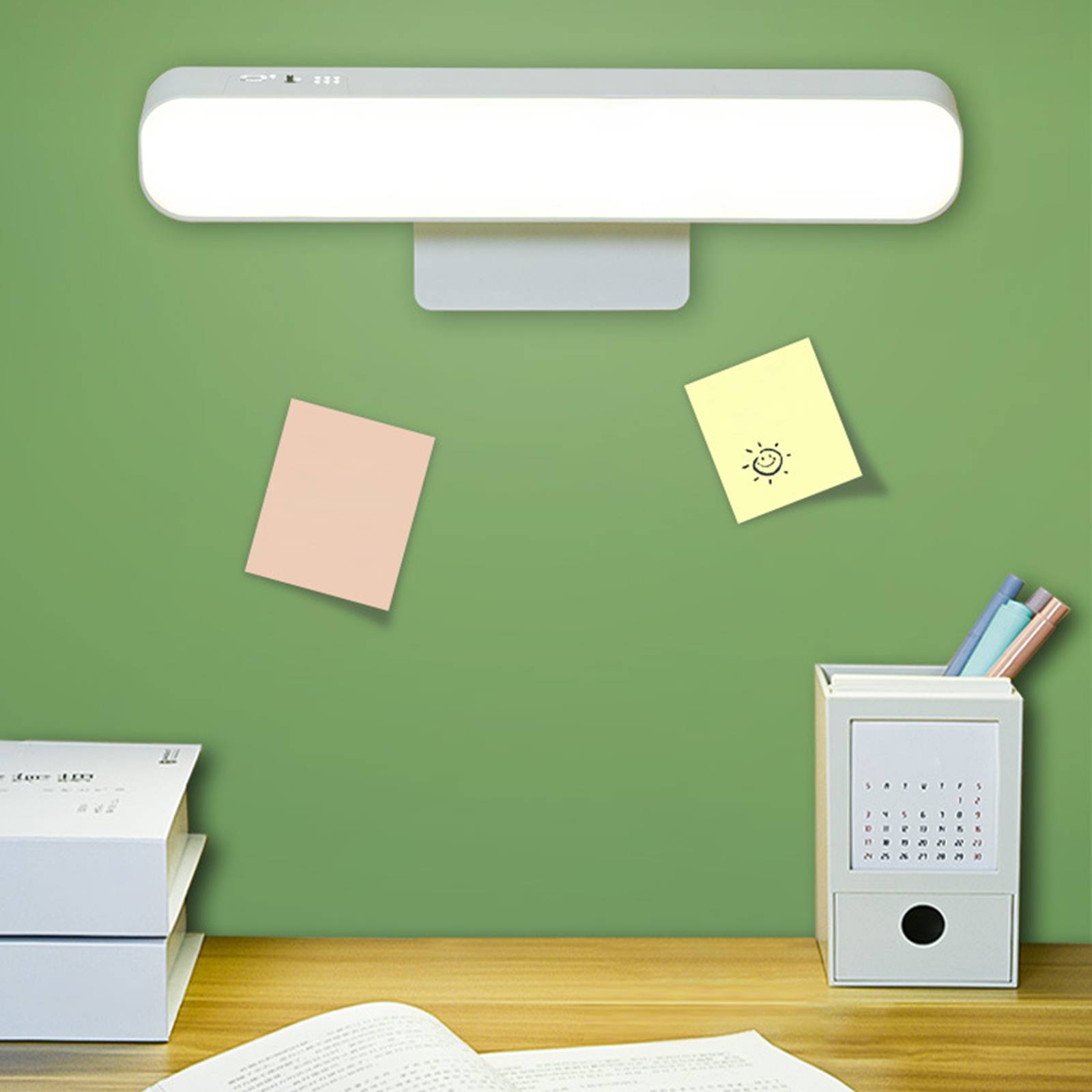 Schreibtisch mit Lampe, Haftnotizen und Kalender. Grüner Hintergrund.