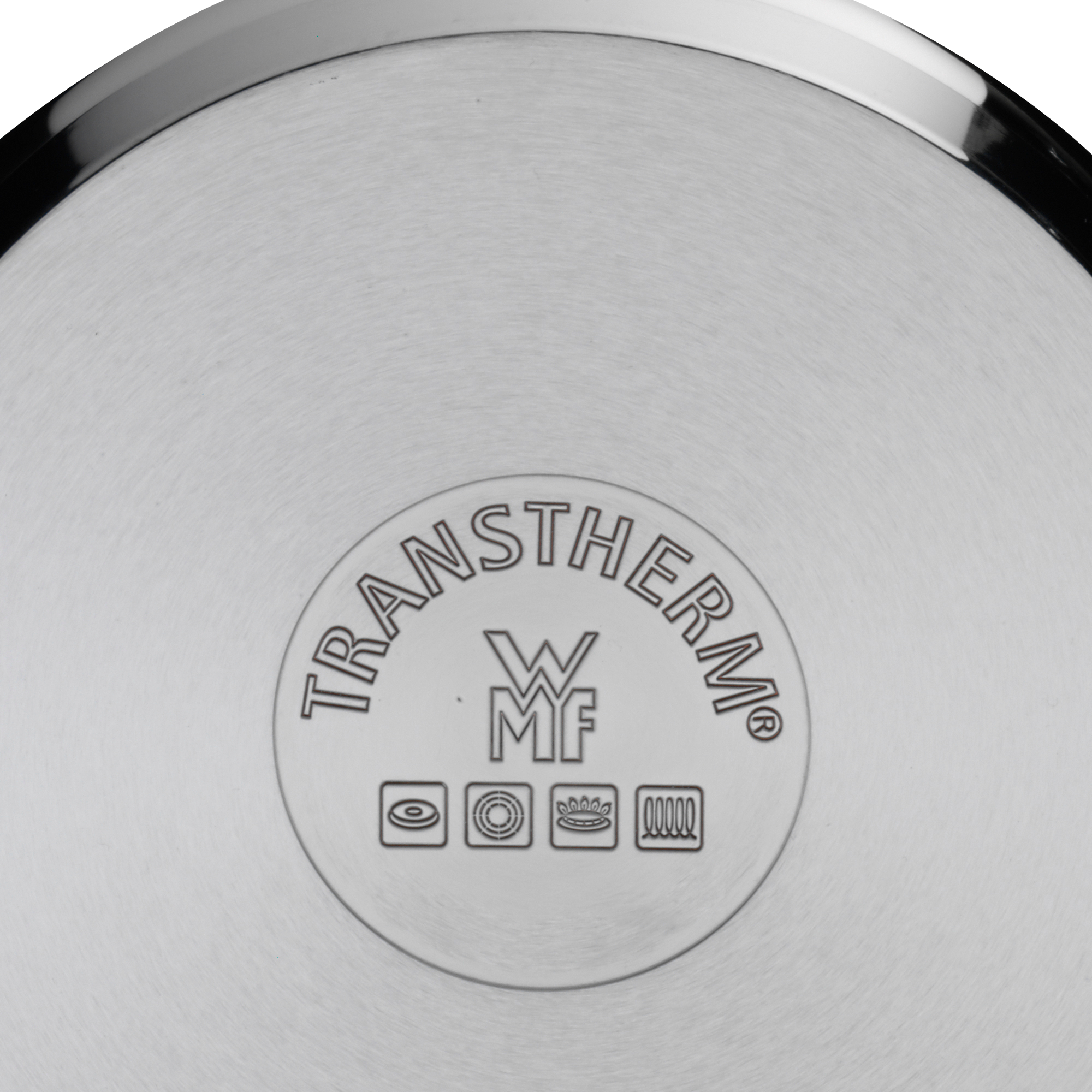Nahaufnahme eines Edelstahlpfannenbodens mit dem TransTherm-Logo und Kochsymbolen eingeprägt.