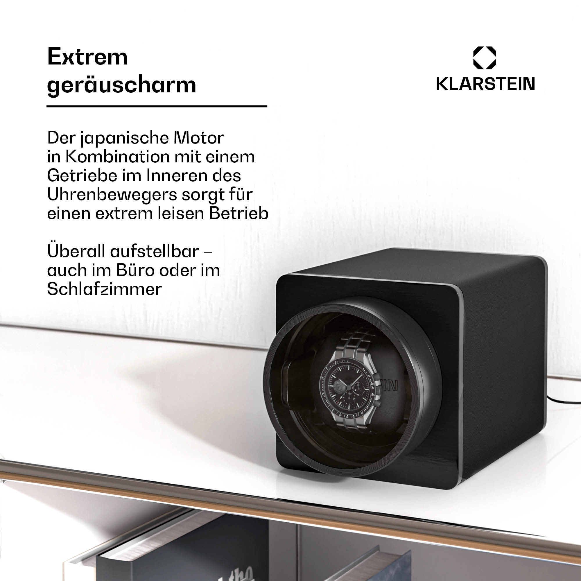 Ein schwarzer Uhrenbeweger mit einer Uhr darin. Der Aufzieher steht auf einer weißen Oberfläche.