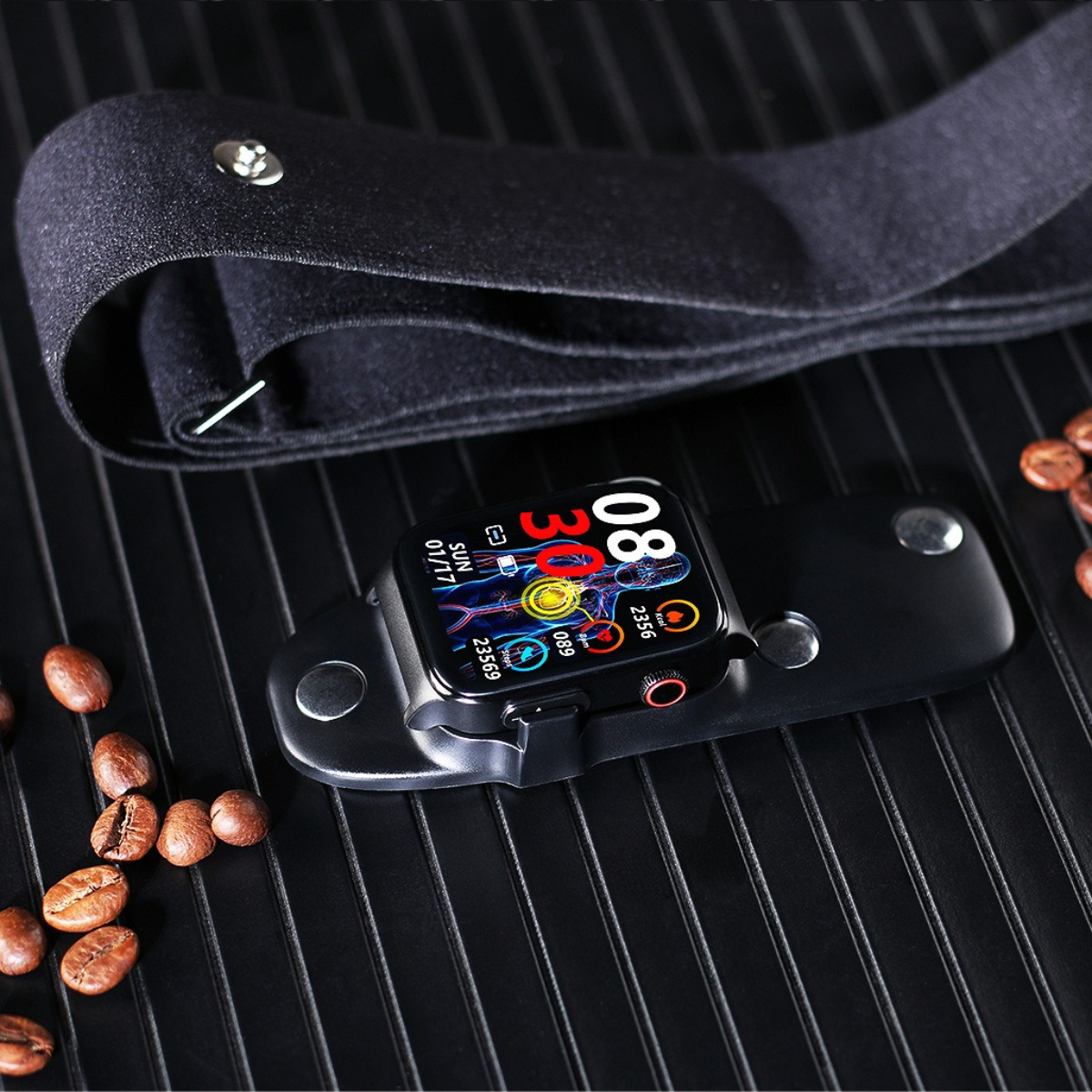 Schwarze Smartwatch auf einem schwarzen Halter. Kaffeebohnen auf schwarzer Oberfläche daneben.