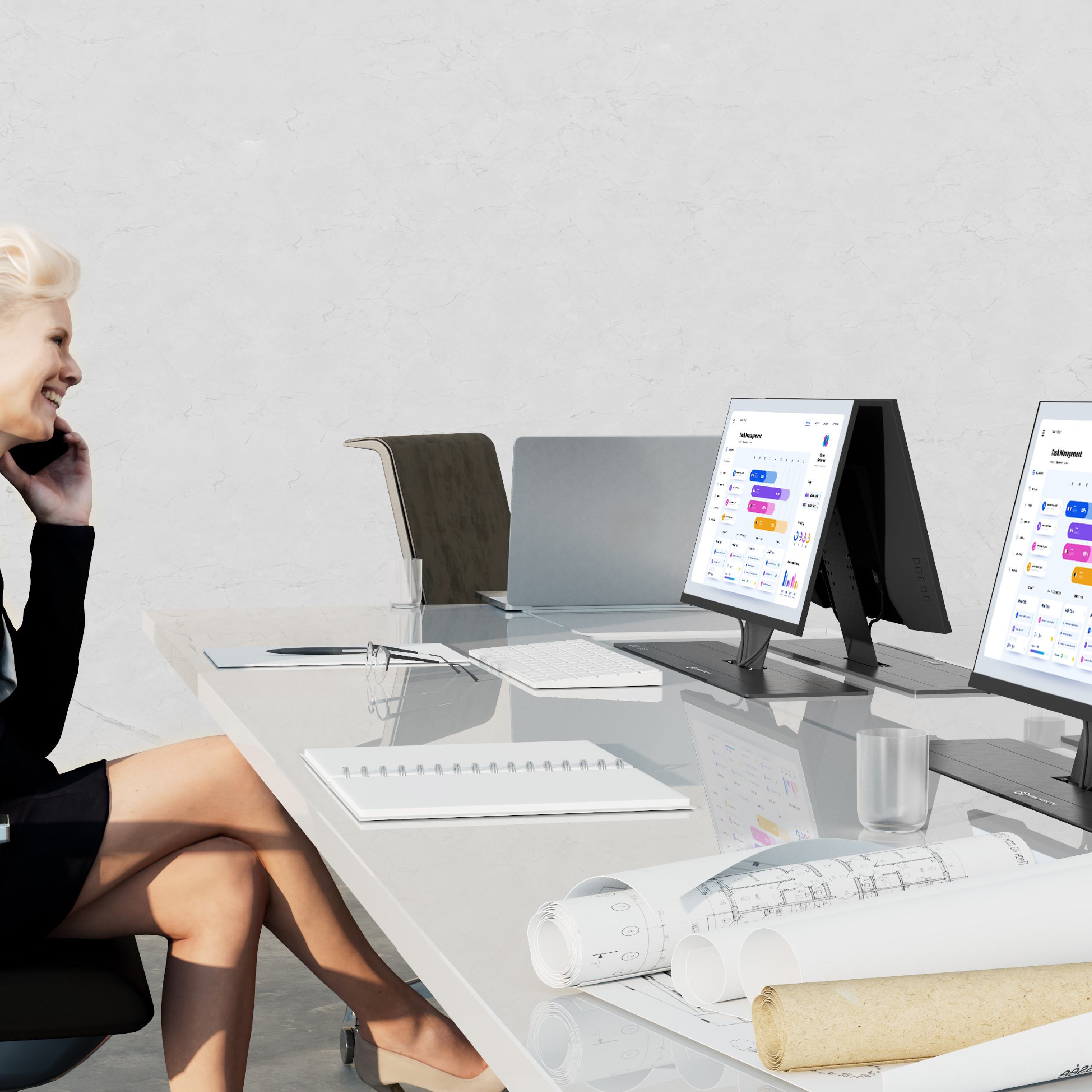 Eine Frau telefoniert an einem Schreibtisch mit Computern. Auf dem Schreibtisch liegen Baupläne.