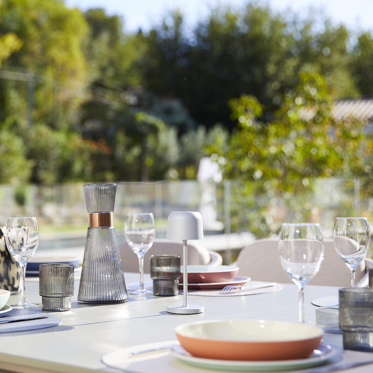 Tisch im Freien mit Gläsern, Dekoration und Essen. Verschwommener Hintergrund mit Bäumen.
