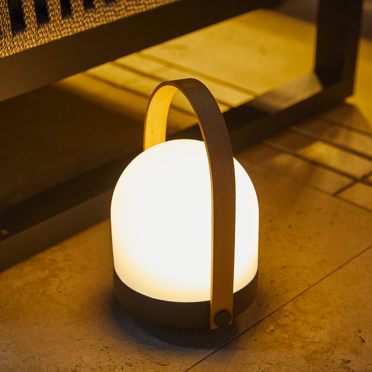 Leuchtende Lampe mit Holzgriff, auf dem Boden platziert. Der Hintergrund ist dunkel.