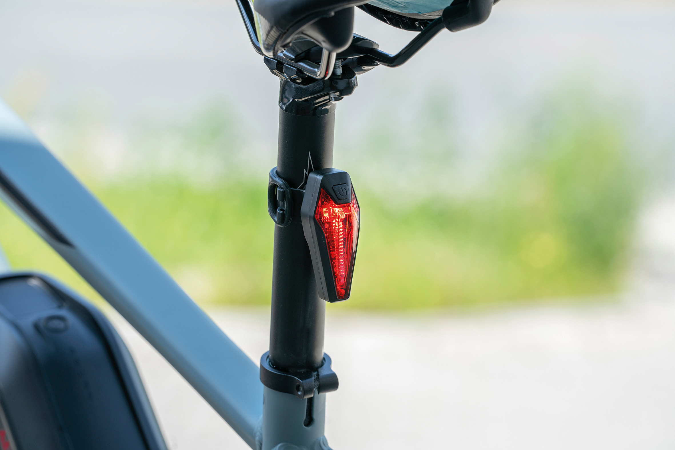 Fahrrad-Sattelstütze mit angebrachtem rotem Rücklicht. Grüner Hintergrund.