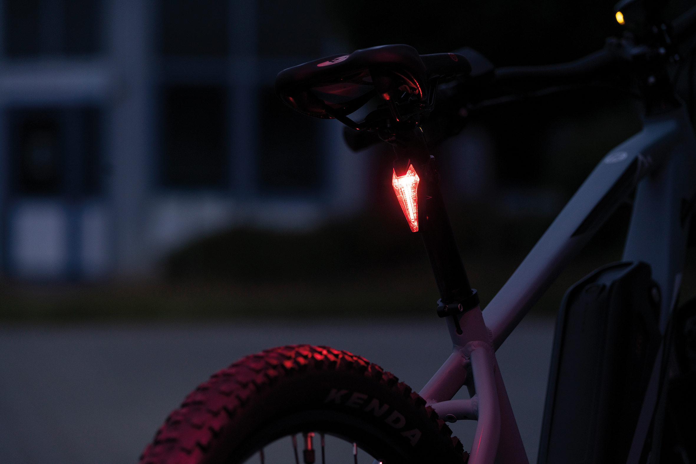 Fahrrad mit rotem Rücklicht bei Dämmerung. Nachtszene mit dunklem Hintergrund.