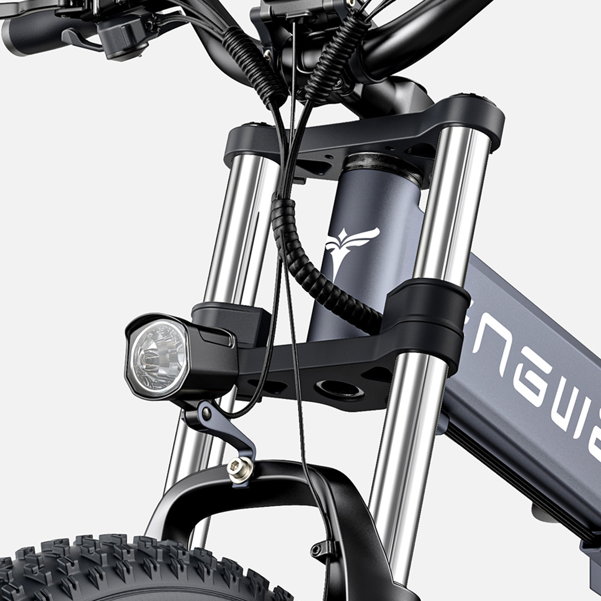 Zbliżenie przodu roweru, z reflektorem, zawieszeniem i kierownicą. Kolory szare i metaliczne.