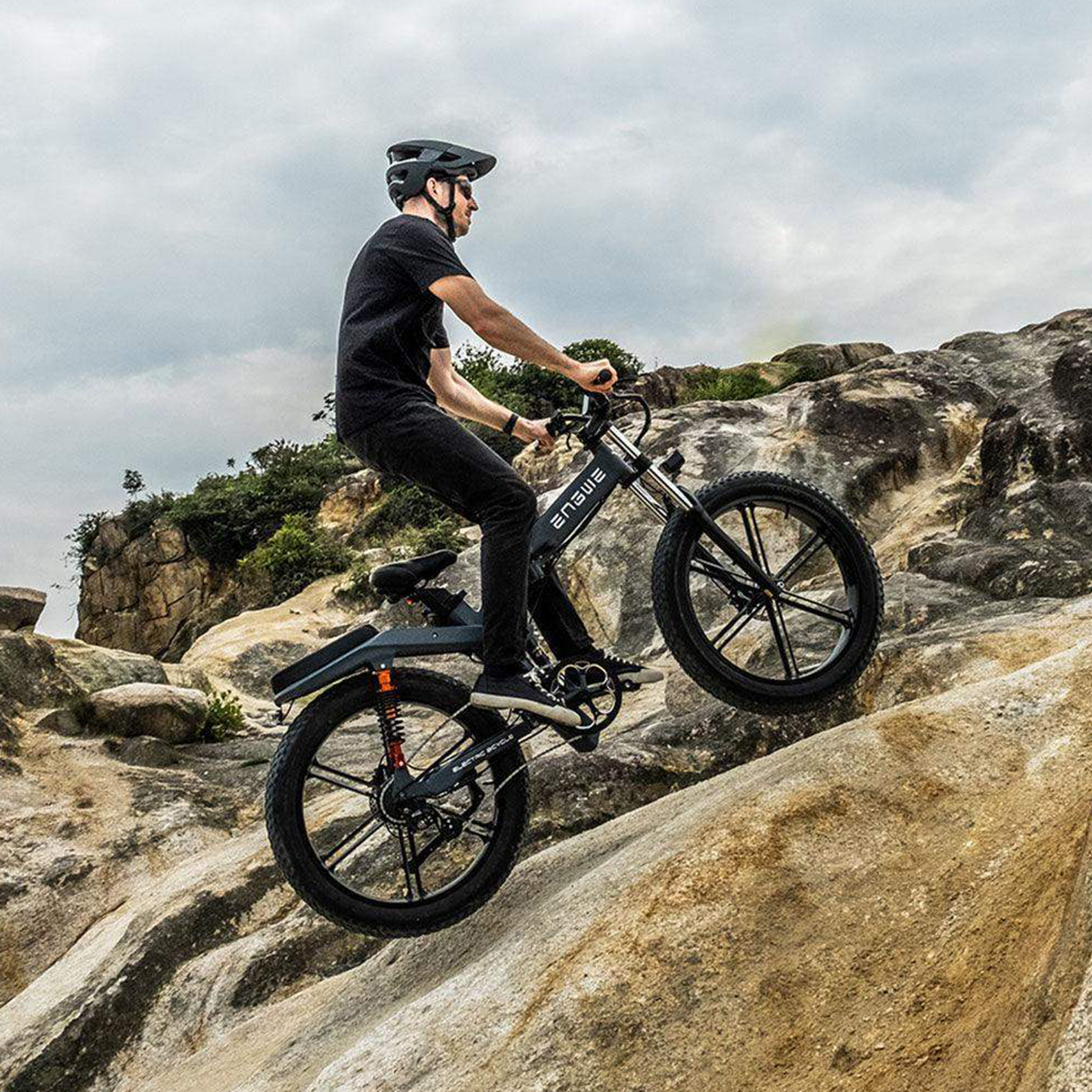 Mężczyzna jadący rowerem elektrycznym pod górę po skalistym wzgórzu, w kasku.