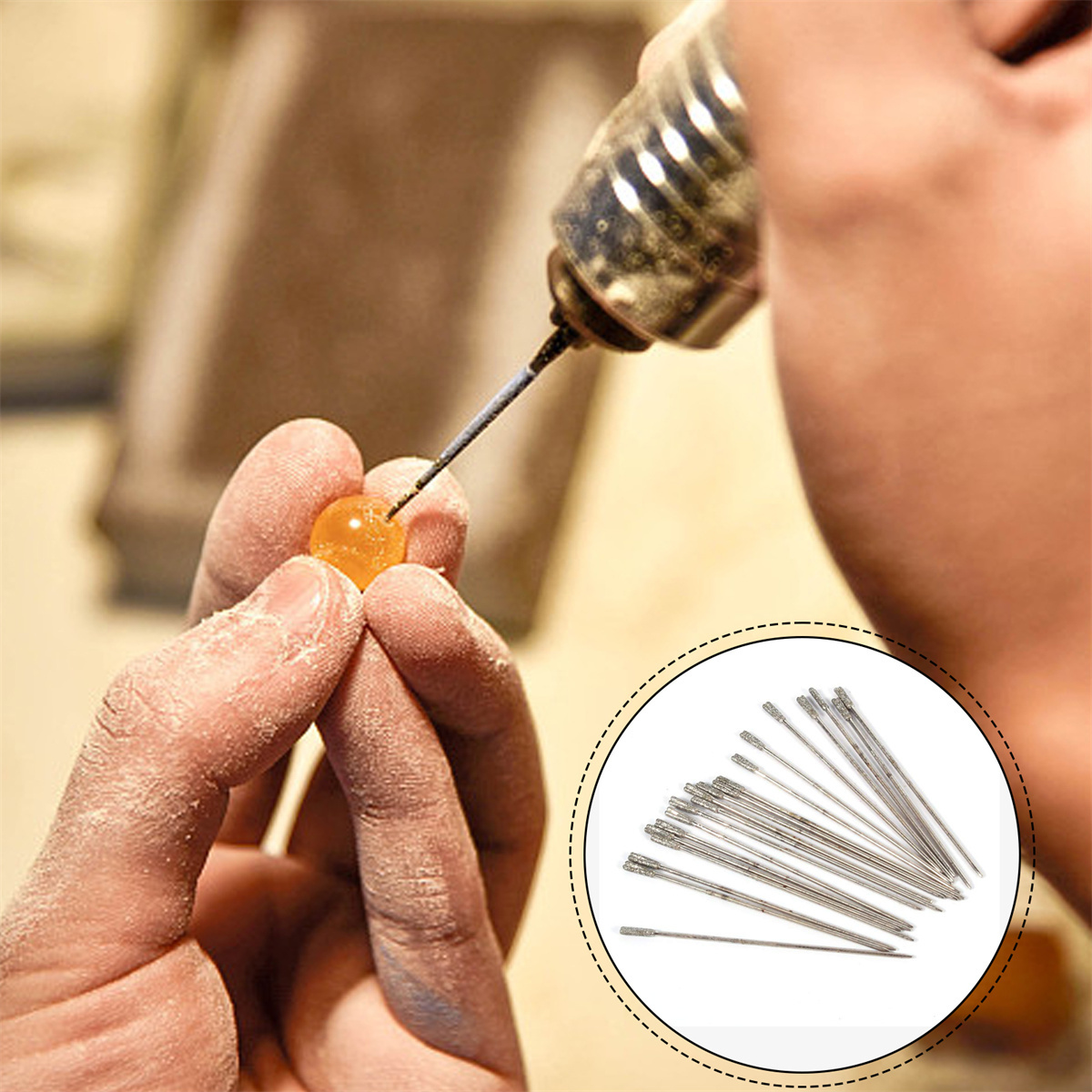 Eine Hand hält einen kleinen, orangefarbenen Edelstein, der gebohrt wird. Mehrere Bohrer sind im Hintergrund.