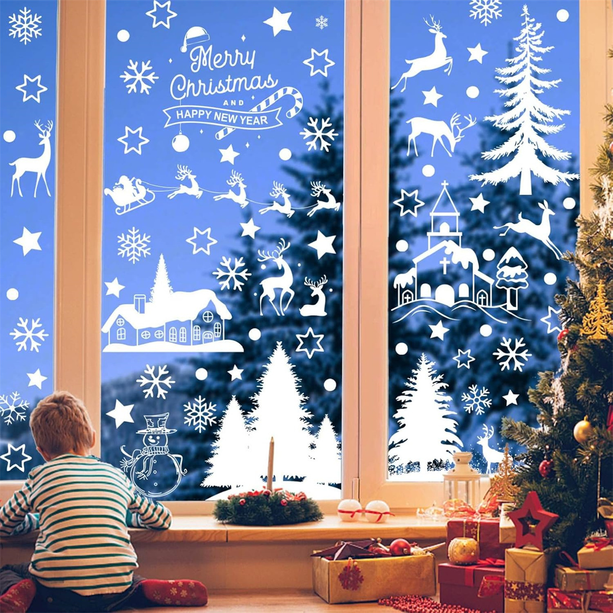 Weihnachtsfenster mit weißen Dekorationen vor blauem Hintergrund. Ein Kind schaut es an.