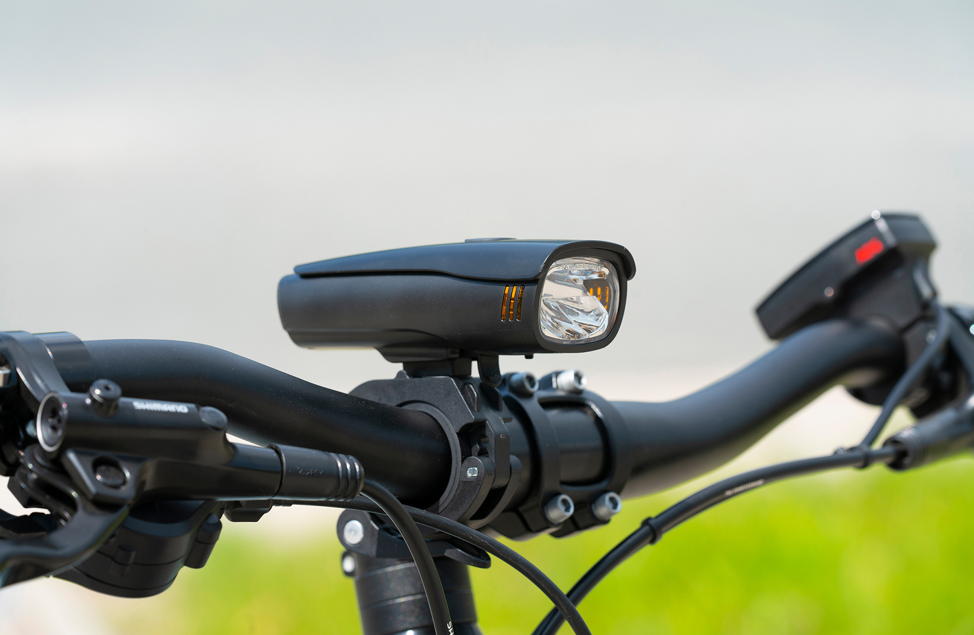 Fahrradlenker mit einem schwarzen Licht befestigt. Das Licht ist eingeschaltet.