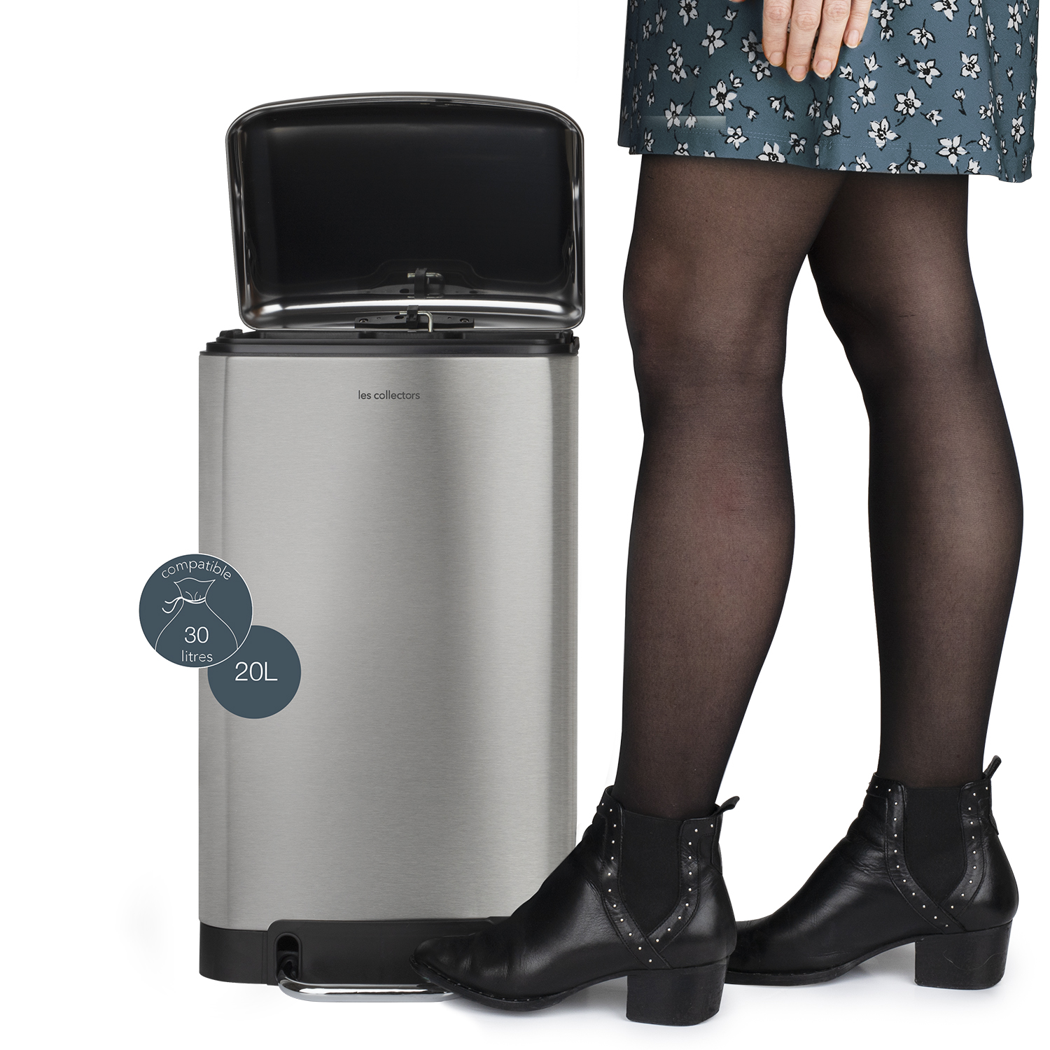 Una donna è in piedi accanto a un bidone in acciaio inossidabile. Il coperchio è aperto. Il bidone ha un'etichetta da 20L e 30L.