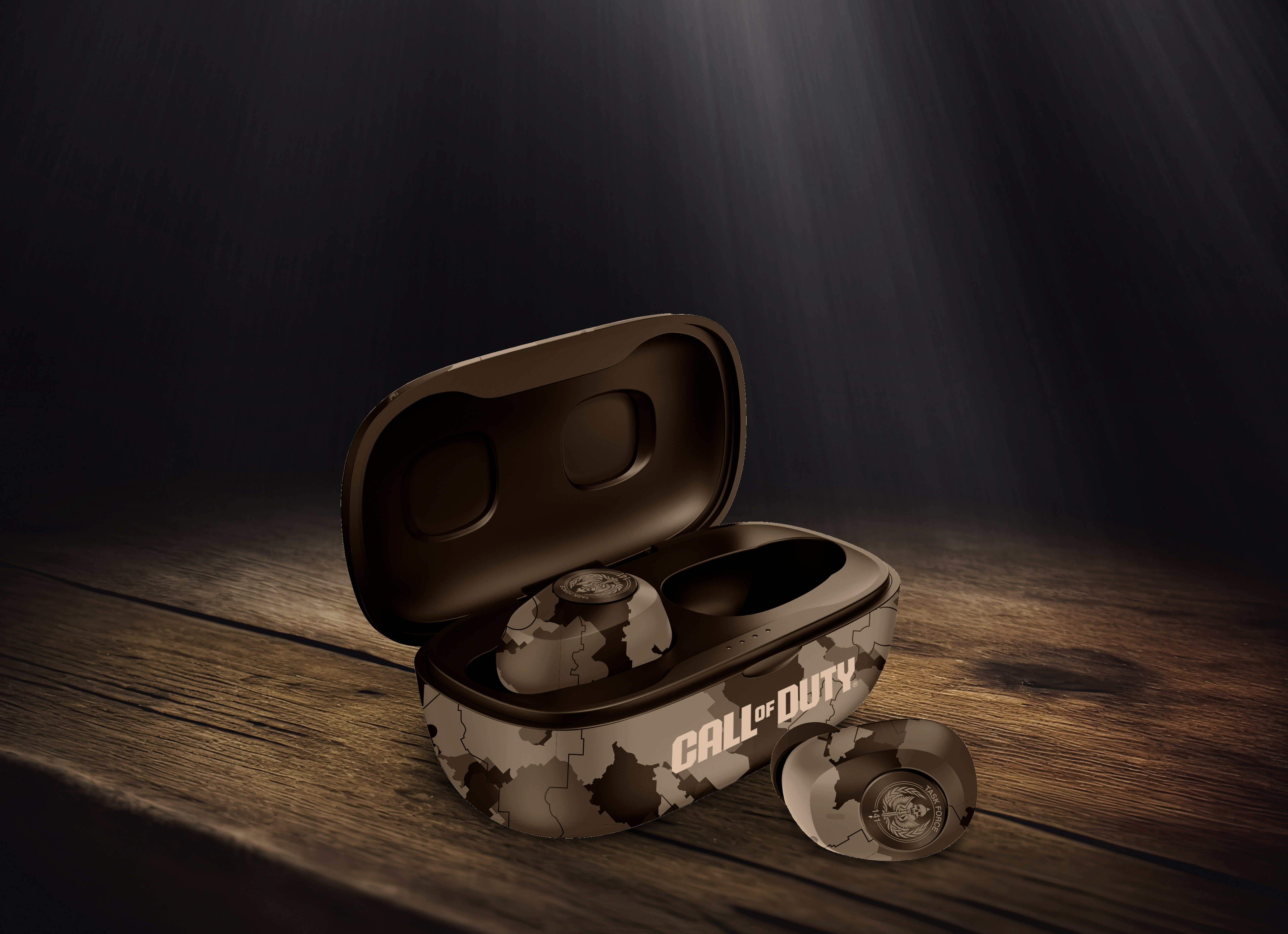 Auricolari in una custodia mimetica con logo Call of Duty su un tavolo di legno.