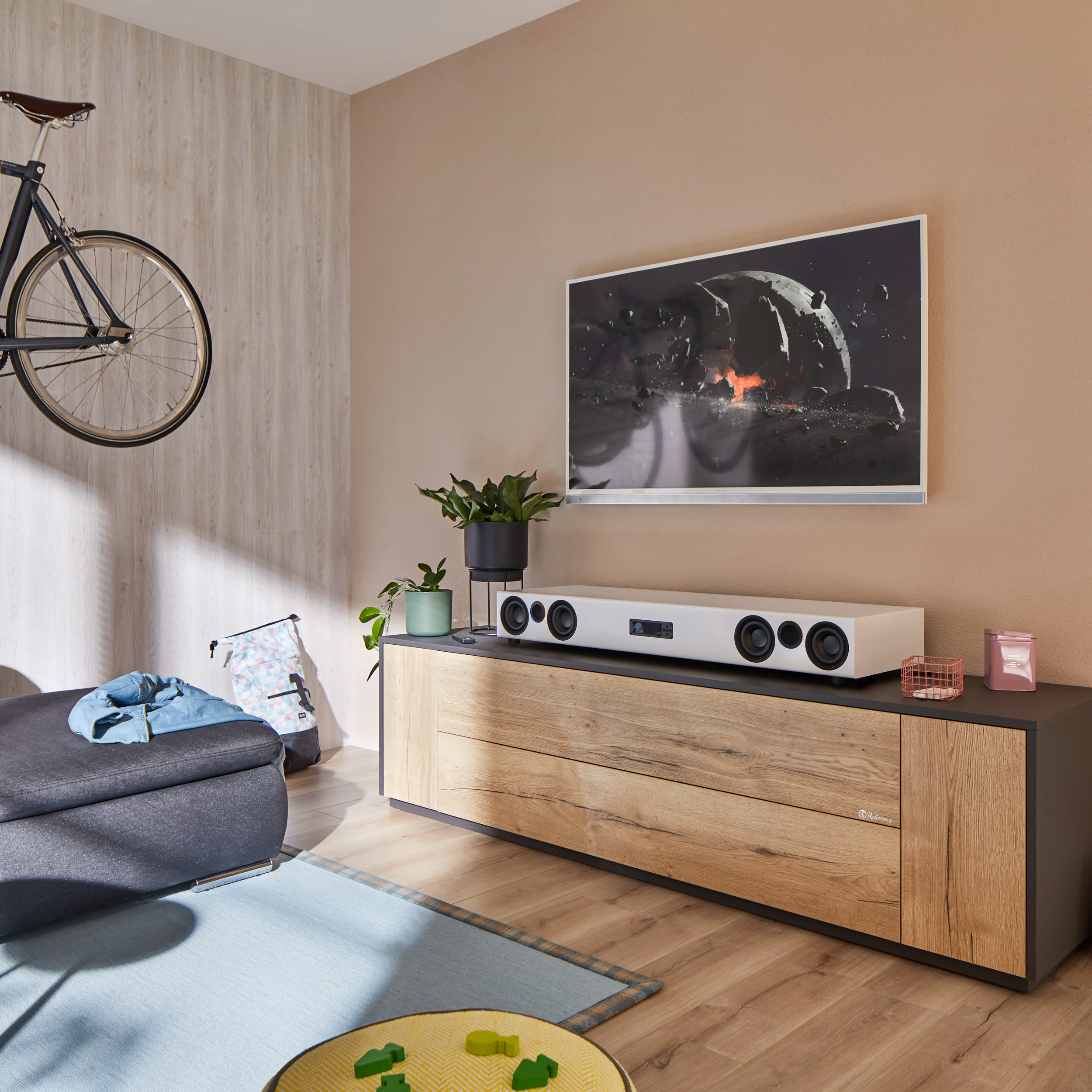 Wohnzimmer mit Fernseher, Soundbar, Fahrrad und Sofa.