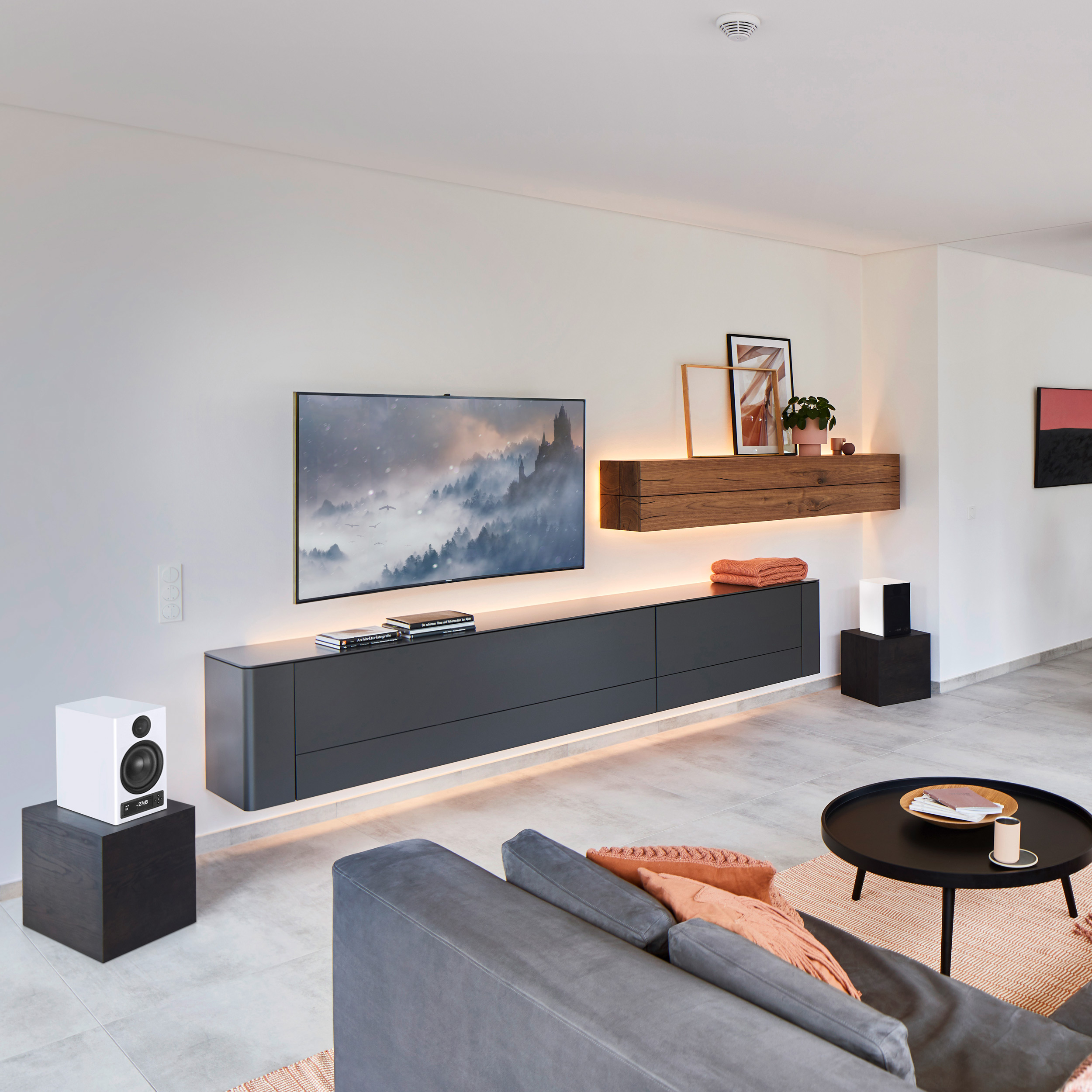 Modernes Wohnzimmer mit TV, Sofa, Lautsprechern und Kunst. Neutrale Farben, Holz.