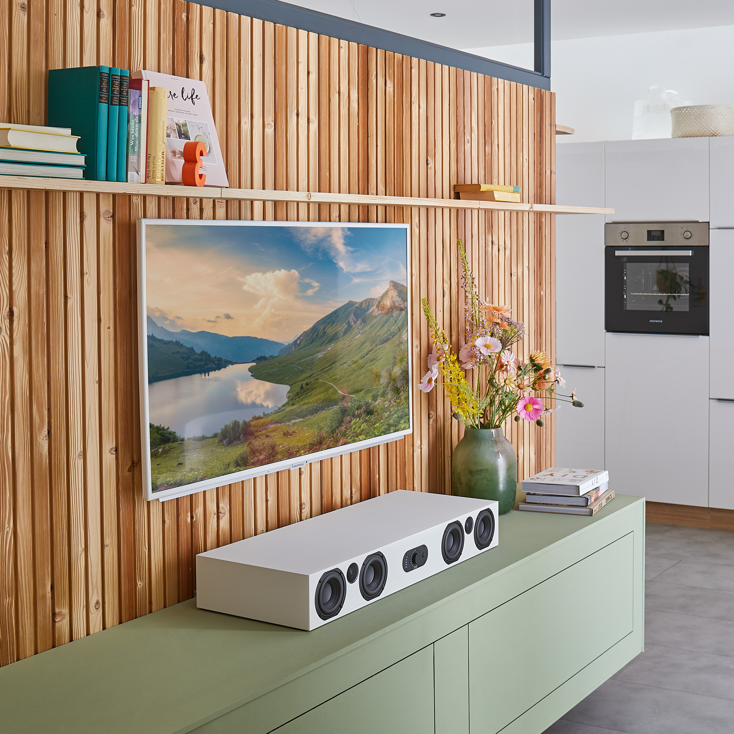 Modernes Wohnzimmer mit Fernseher an einer Holzwand, Soundbar und Blumen in einer Vase.
