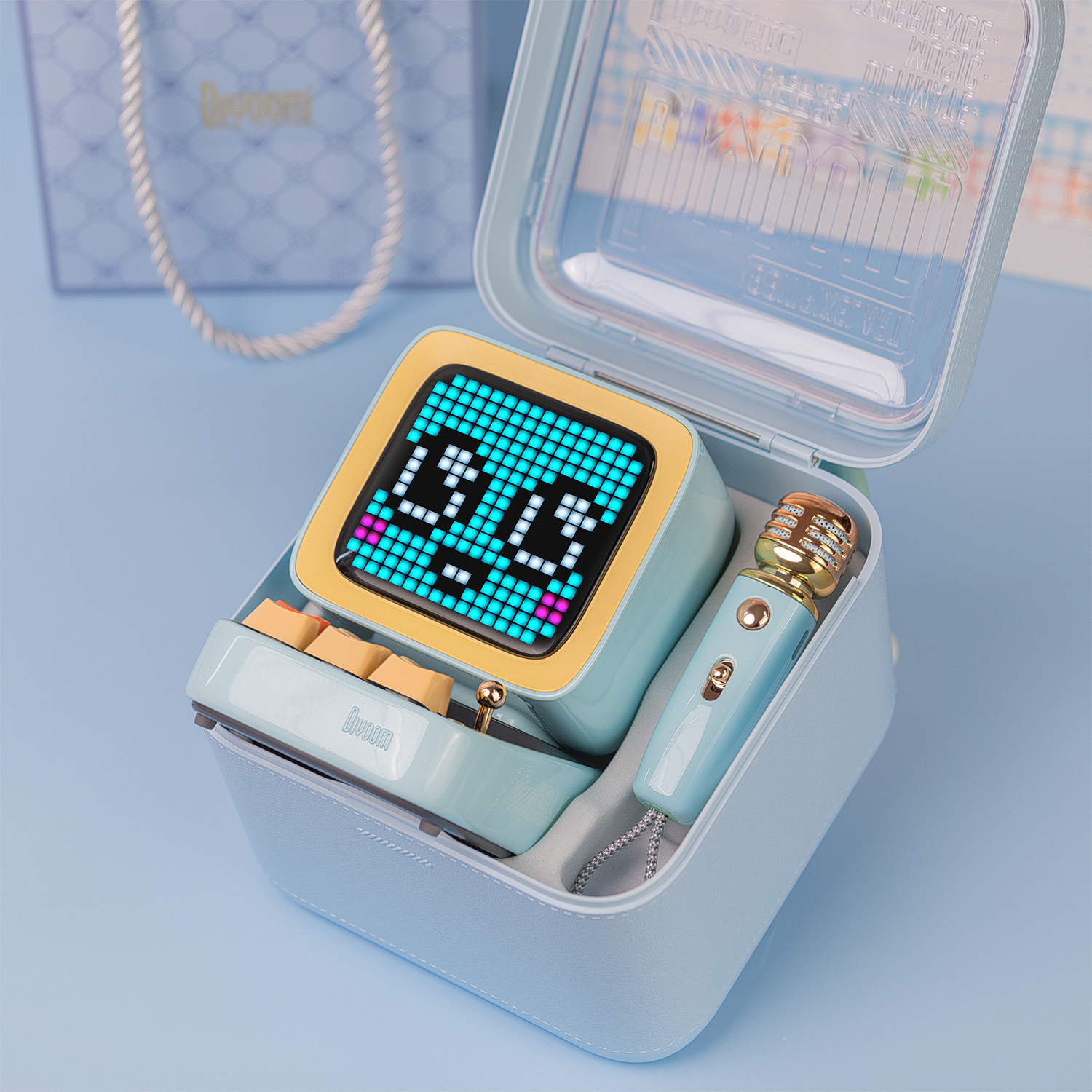 Een blauwe Divoom-luidspreker in een hoesje. Het heeft een scherm, knoppen en een microfoon. De achtergrond is blauw.