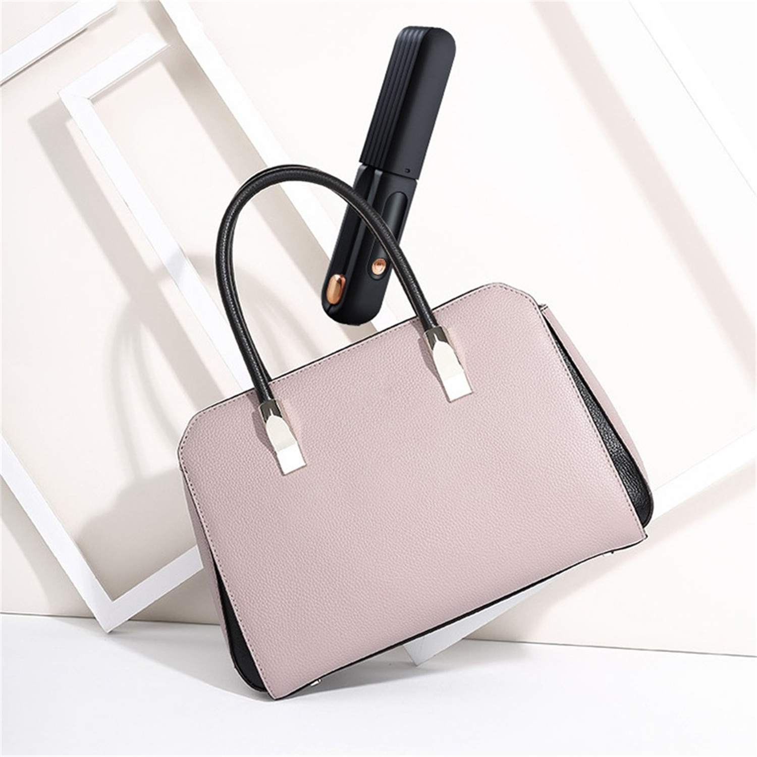 Eine rosa Handtasche und ein schwarzer Haarglätter sind vor einem weißen Hintergrund mit Rahmen positioniert.