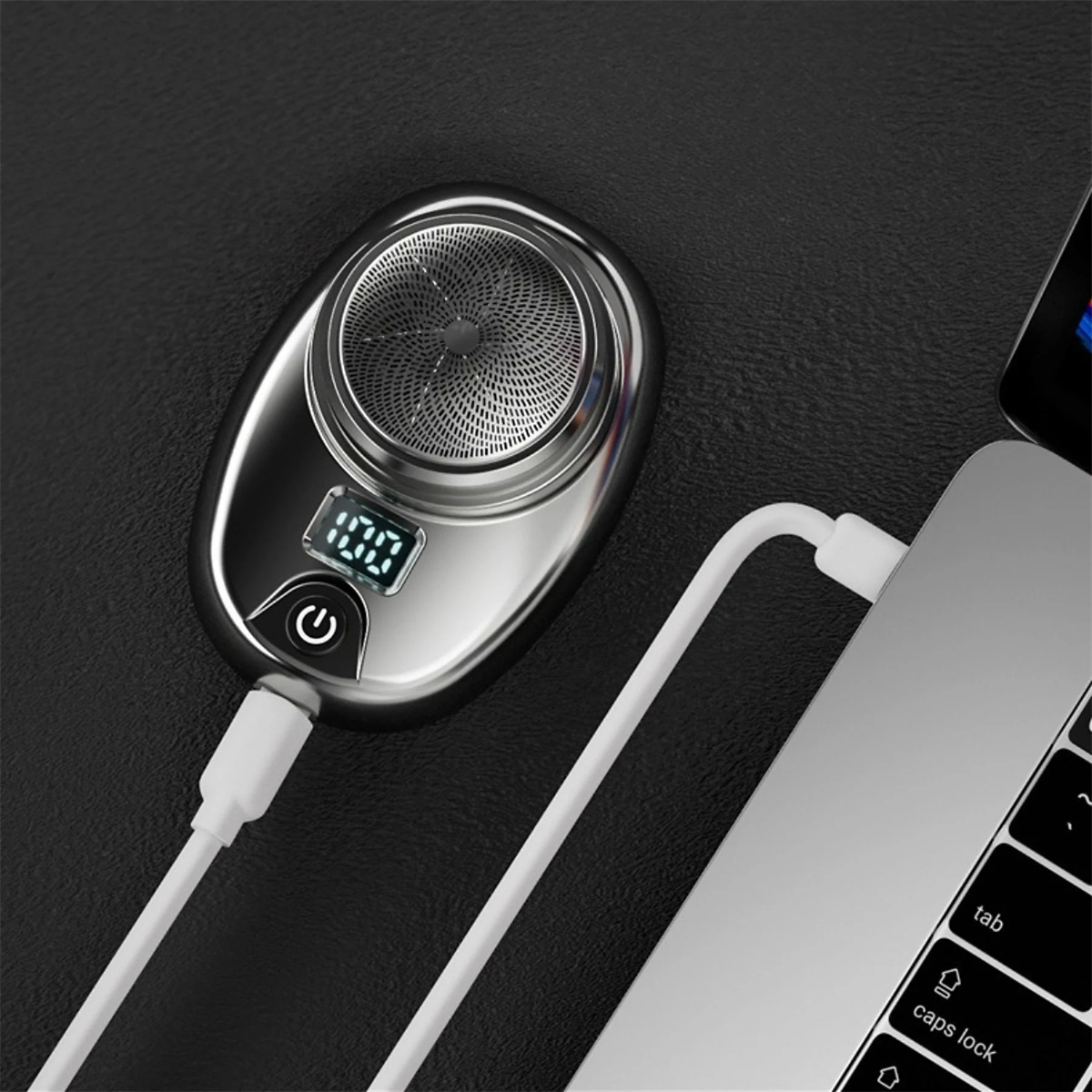 Elektrischer Rasierer, der mit einem weißen USB-Kabel und einem Laptop geladen wird.