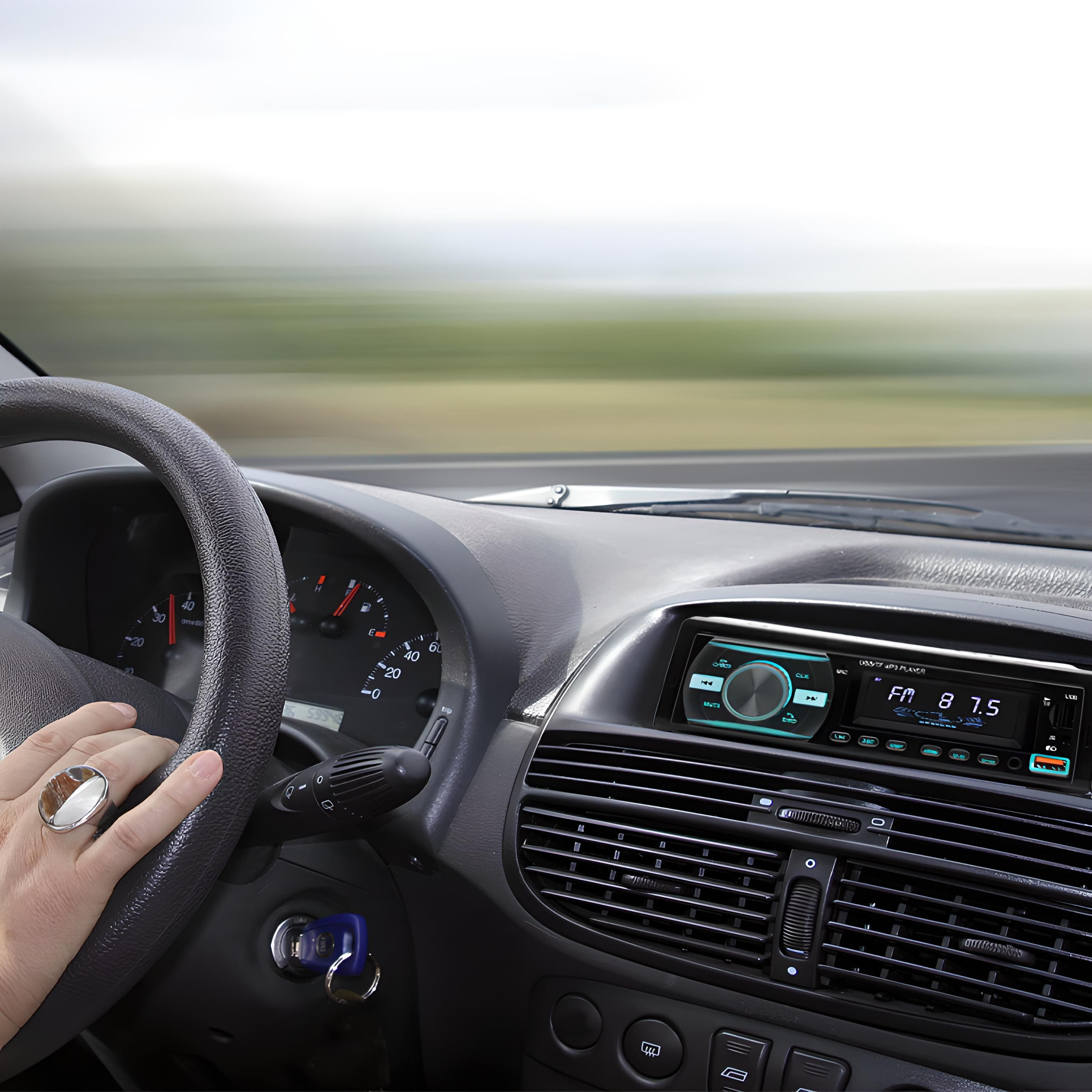 Innenaufnahme eines Autos mit der Hand des Fahrers am Lenkrad, Radio und Armaturenbrett sichtbar.