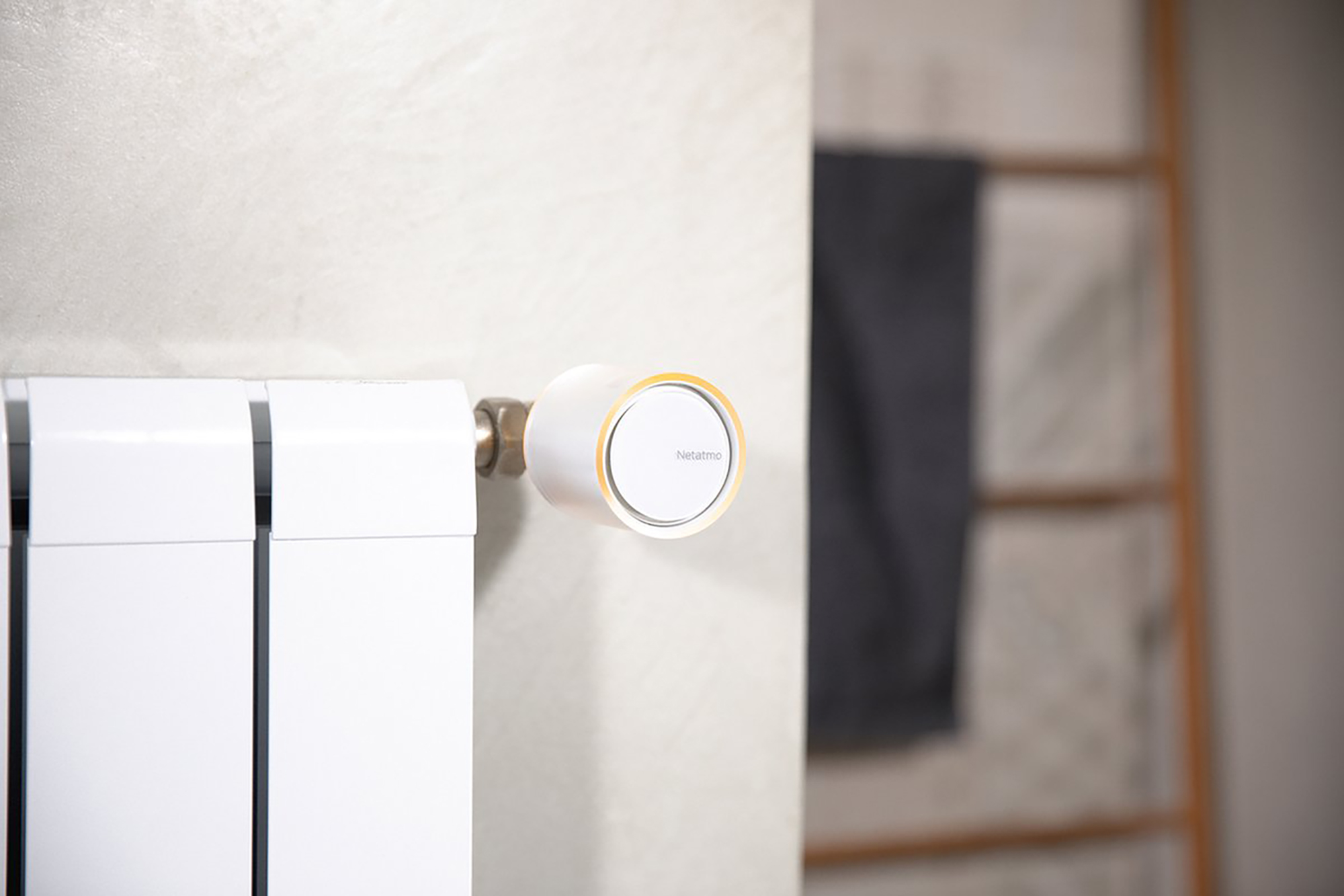 A smart thermostat mounted on a white radiator in a neutral-toned room.