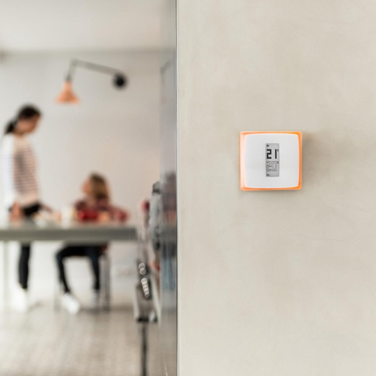 A thermostat displays 21 degrees. Two people are visible in the background.