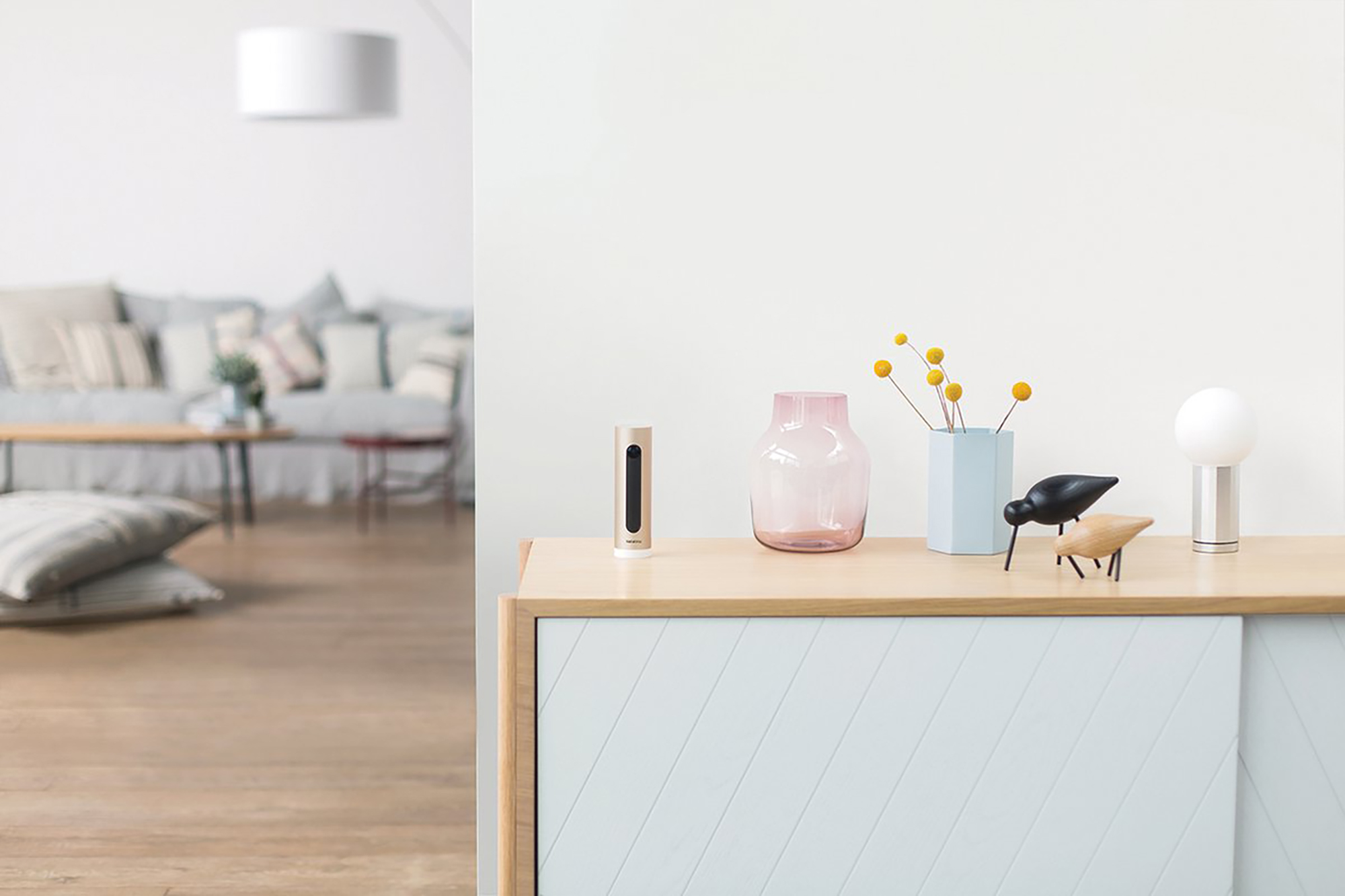 Un comodino con decorazioni: vaso, statuette, lampada. Soggiorno sullo sfondo.