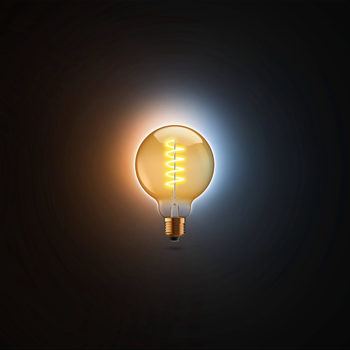 A lit, vintage-style light bulb against a dark background with blue and orange hues.