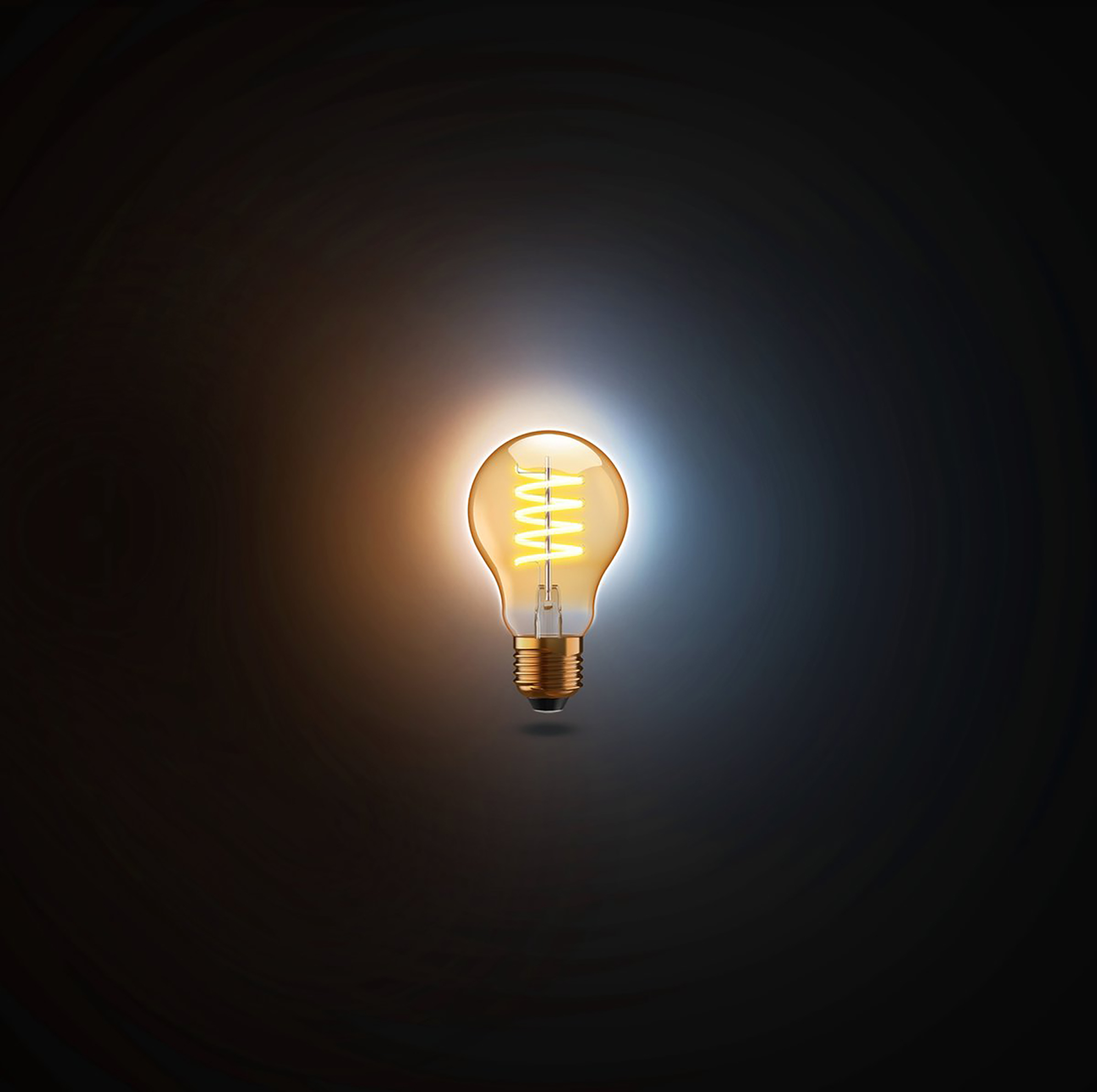 Glowing light bulb with a filament centered in the dark background.