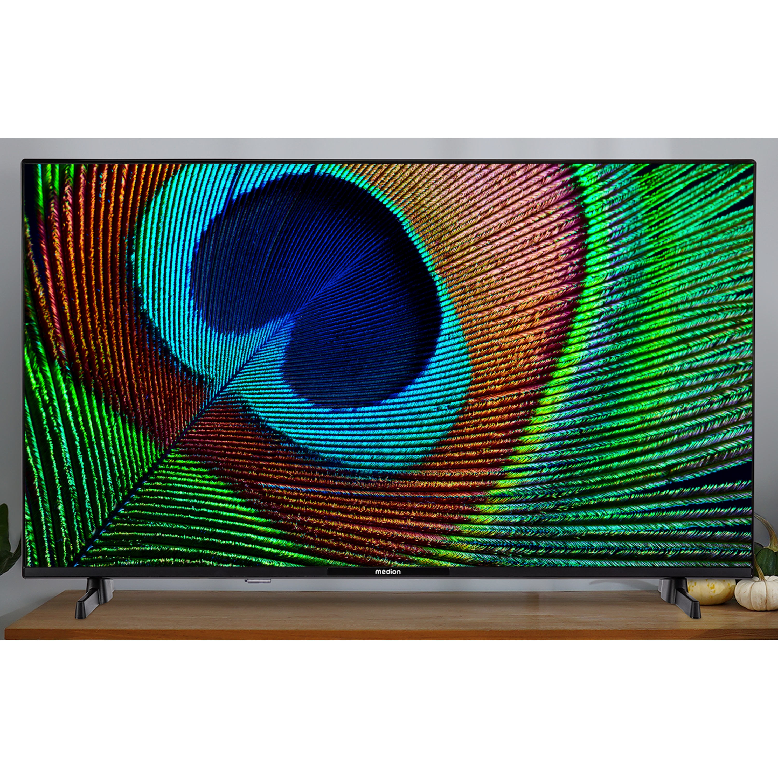 Een tv-scherm met een pauwenveer afbeelding. De tv staat op een houten oppervlak.