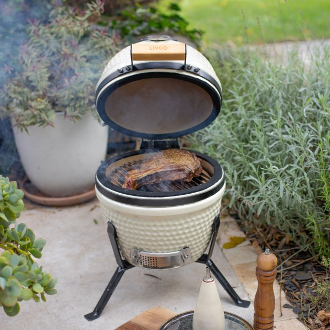 Kleiner Außengrill mit einem Steak, das darauf brät, auf einer Steinterrasse.