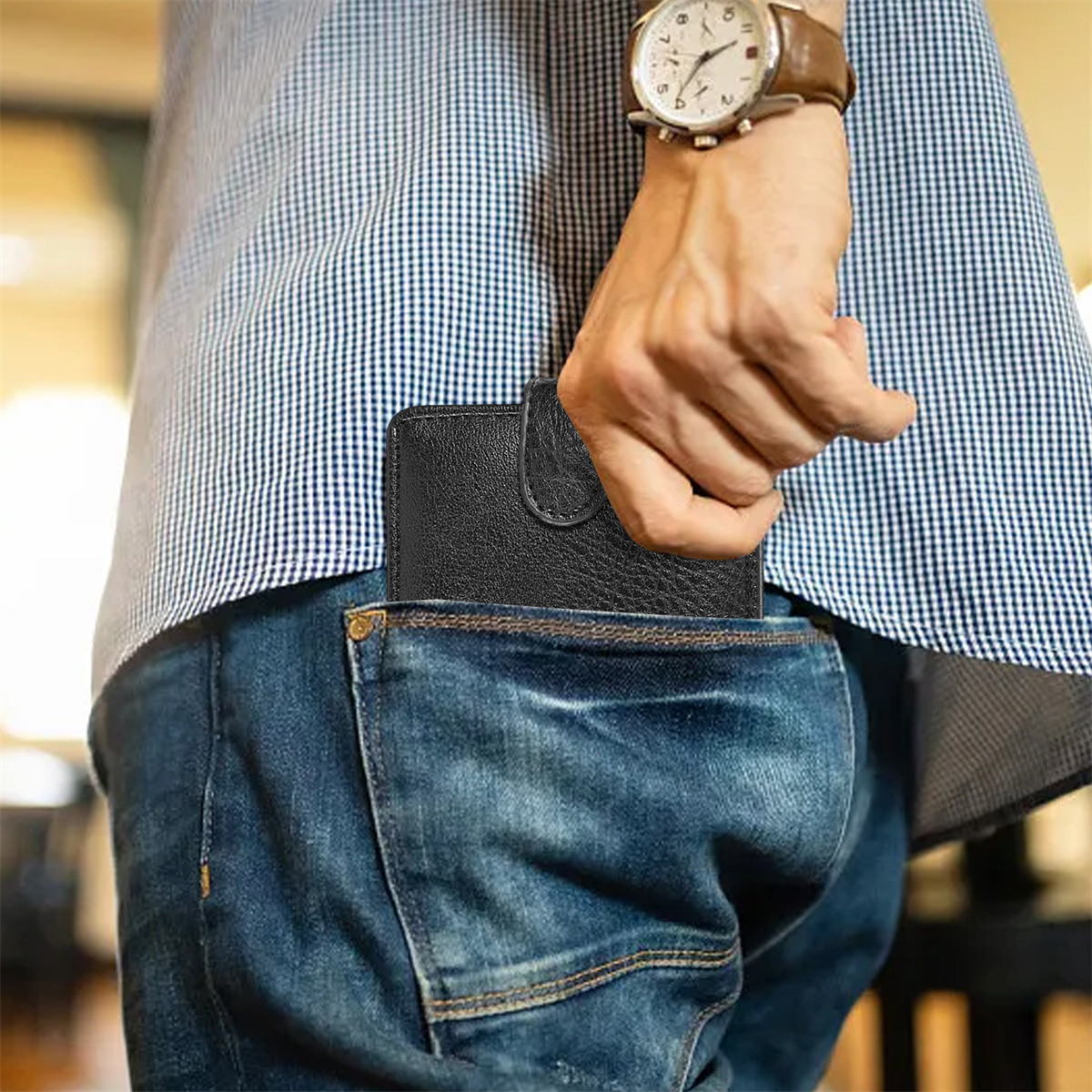 Eine Hand zieht ein schwarzes Portemonnaie aus einer Jeans-Tasche.