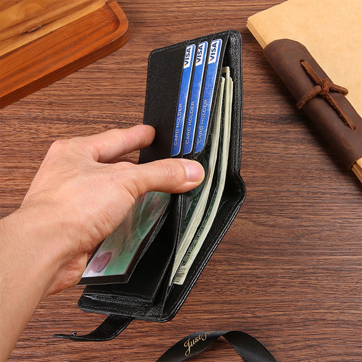 Die Hand einer Person öffnet eine schwarze Geldbörse, gefüllt mit Geld und Karten.