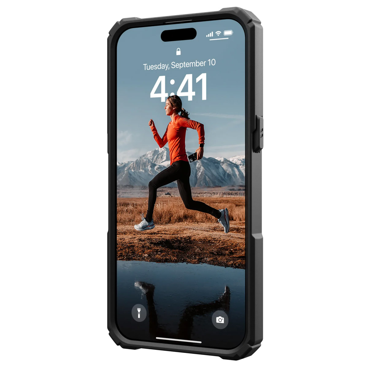 iPhone que muestra a una mujer corriendo en montañas. Lleva camisa naranja y leggings negros.