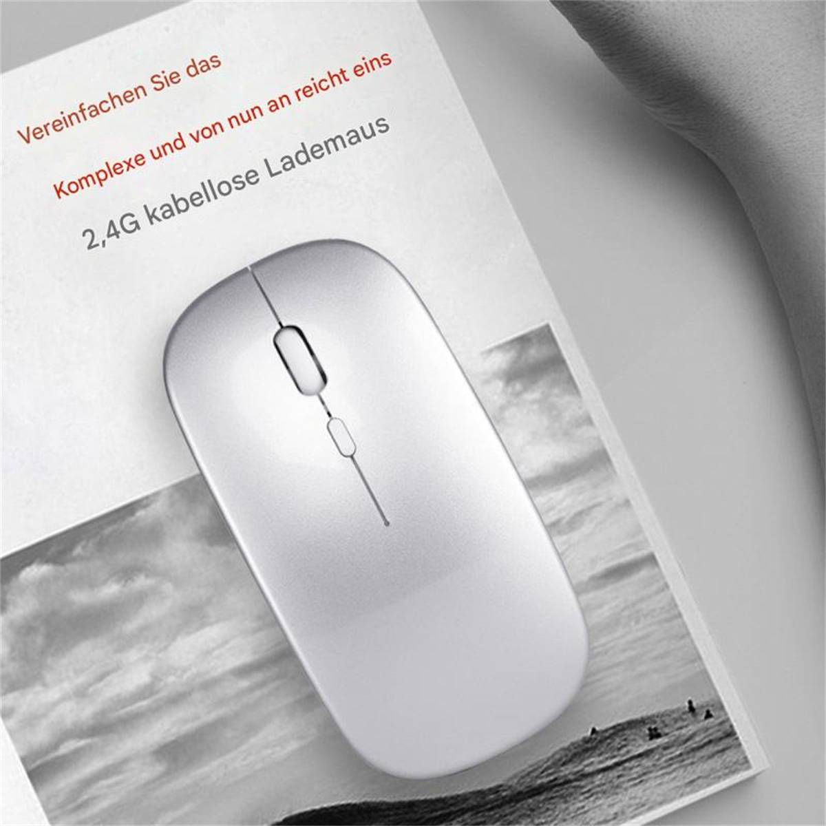 Eine silberne Maus auf Papier. Text auf Deutsch. Die Maus ist kabellos und hat ein Scrollrad.