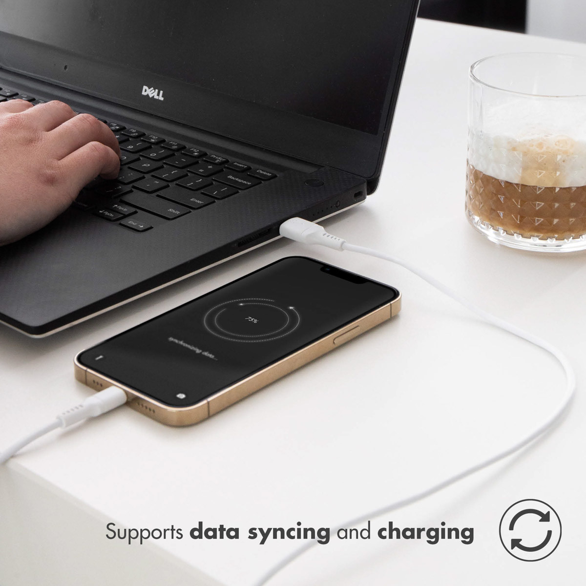 Un téléphone se chargeant à côté d'un ordinateur portable. Une main tape. Texte: Prend en charge la synchronisation et la charge des données.