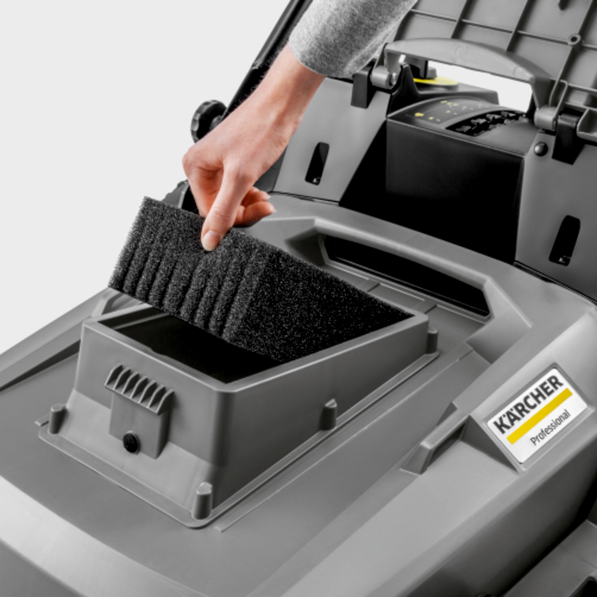 Hand setzt Filter in grauen Karcher Rasenmäher ein. Karcher-Logo sichtbar.