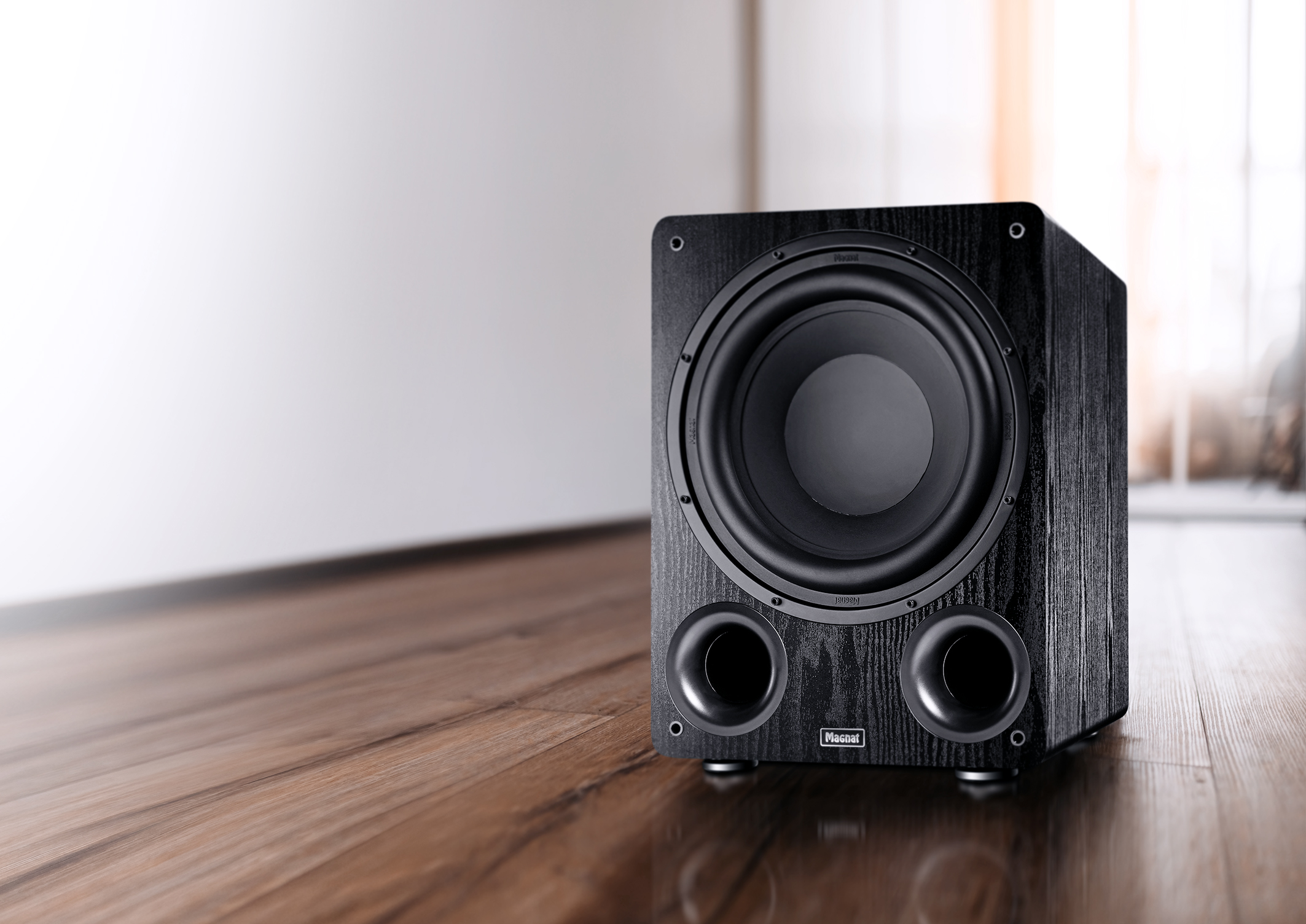 Ein schwarzer Holz-Subwoofer auf einem Holzboden.
