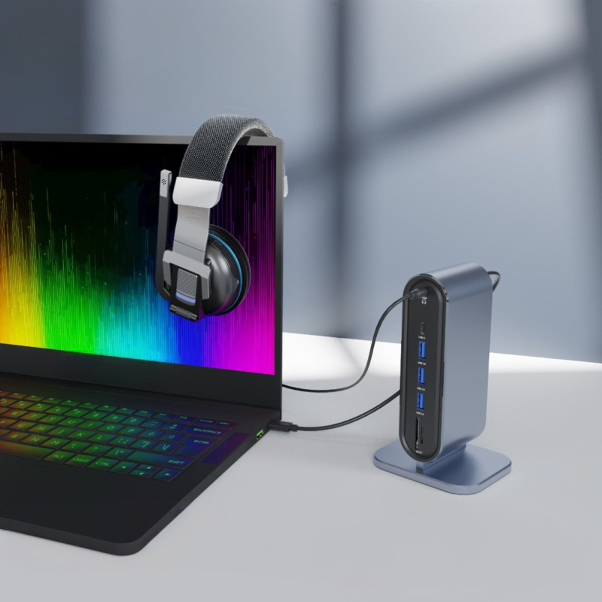 Laptop mit Kopfhörern, die vom Bildschirm hängen, verbunden mit einem USB-Hub mit Smartphone und anderen Anschlüssen.