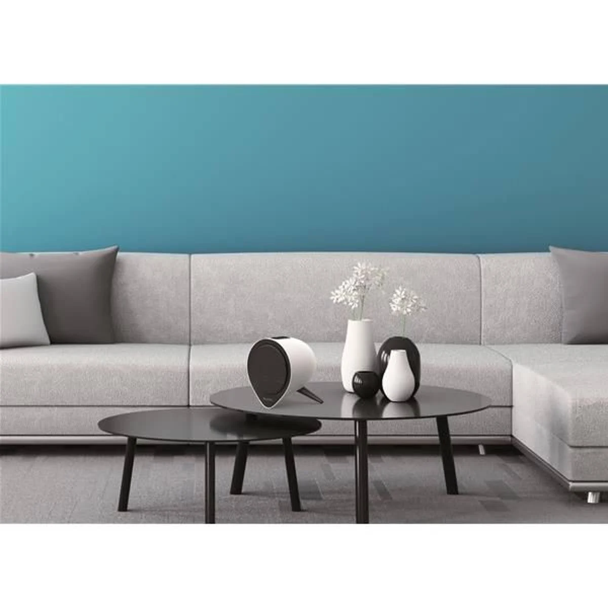 Nowoczesny salon z szarą sofą, dwoma okrągłymi stołami i białym grzejnikiem.