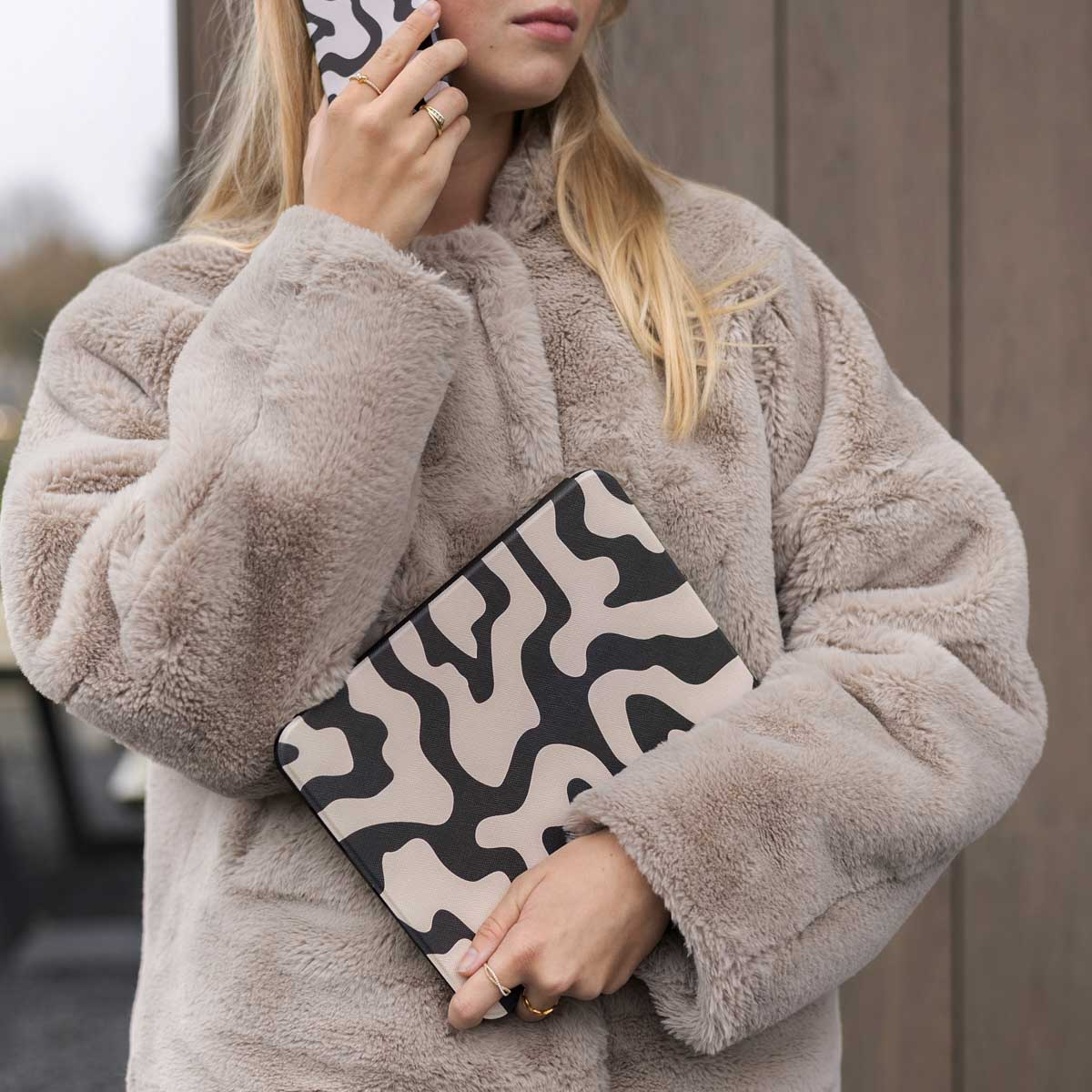 Woman with a beige fur coat is holding a tablet case.