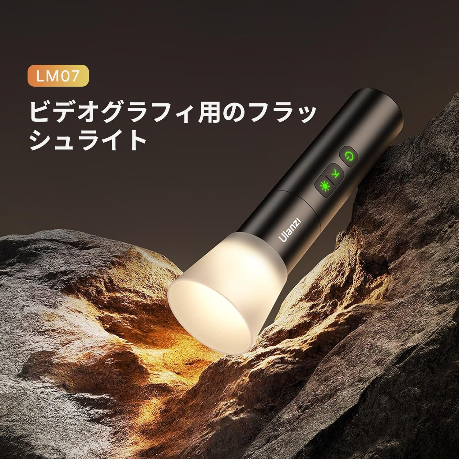 Czarna latarka emituje jasne światło na skale. Widoczne przyciski. Nazwa produktu po japońsku na górze.