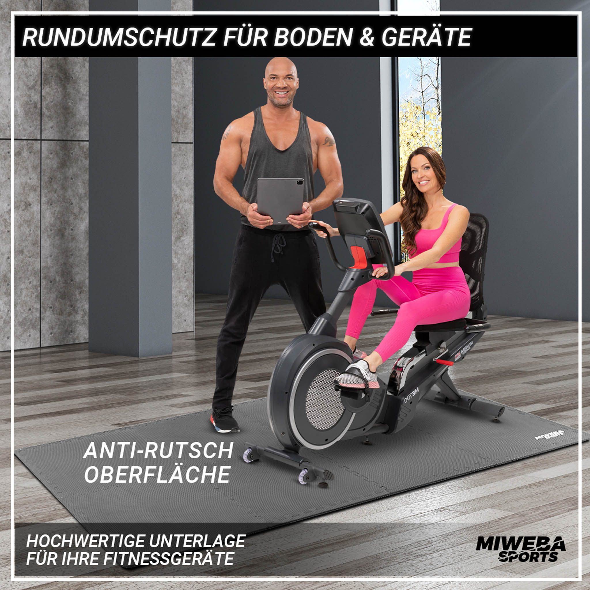 Mann und Frau auf einer Matte. Frau sitzt auf einem Liegefahrrad. Text auf der Matte. Grauer Hintergrund.