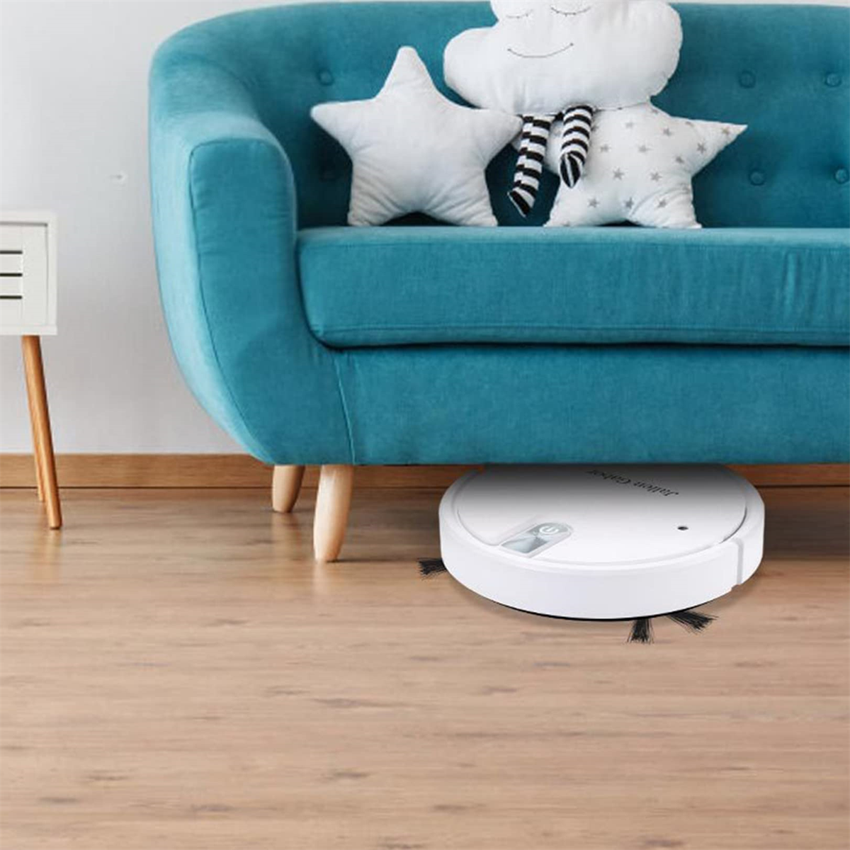 Ein weißer Roboter-Staubsauger auf einem Holzboden in der Nähe eines türkisfarbenen Sofas.