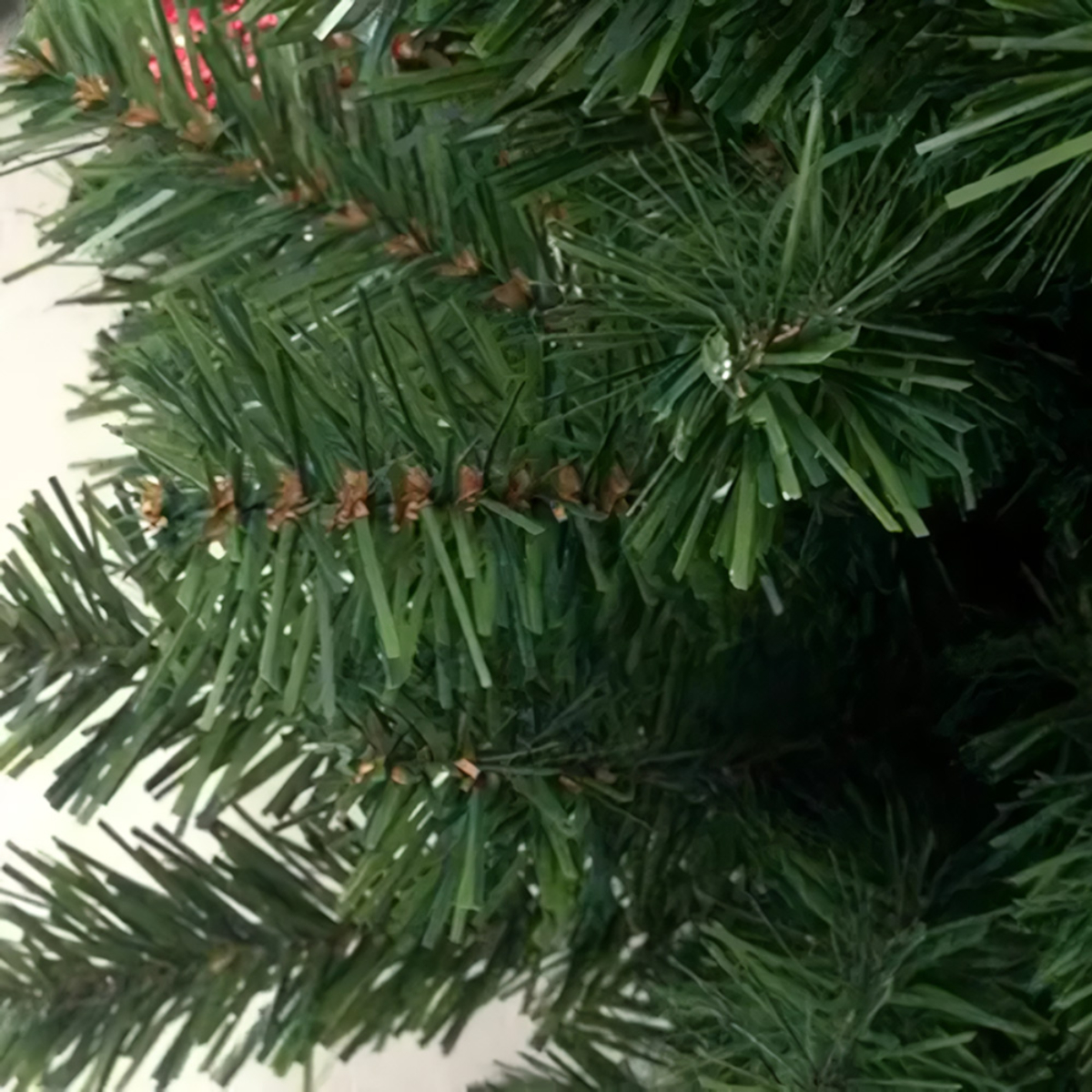 Primer plano de ramas verdes de un árbol de Navidad artificial.