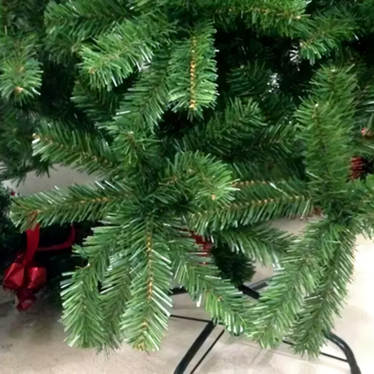 Primer plano de un árbol de Navidad artificial verde, con ramas y agujas visibles.