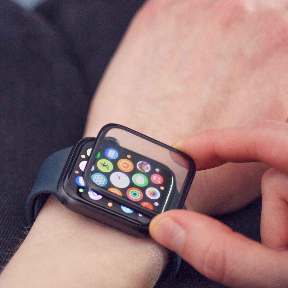 Eine Person bringt einen Displayschutz auf einer Smartwatch an. Die Uhr ist am Handgelenk.