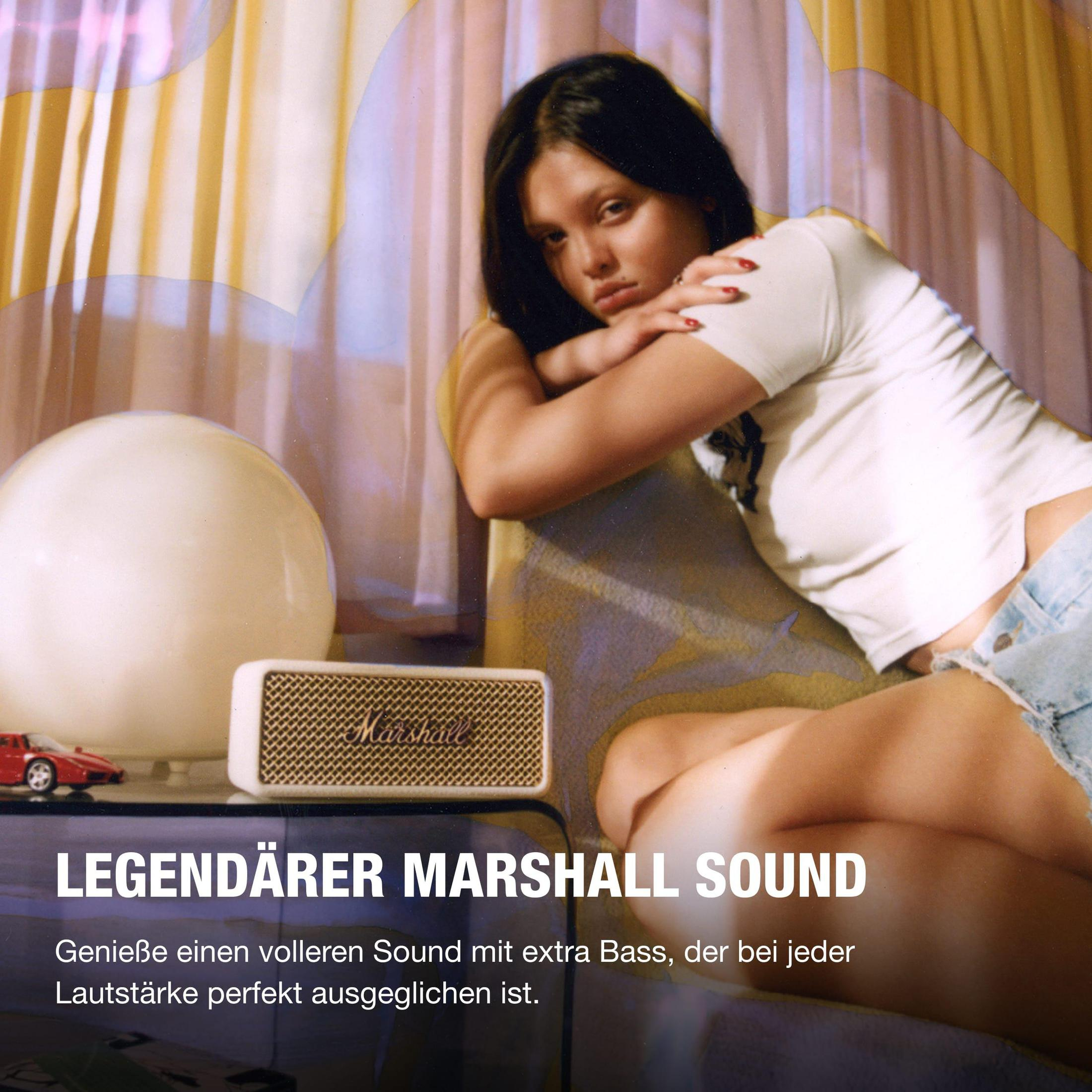 Mujer sentada junto a un altavoz. Producto de sonido Marshall con texto en la parte inferior.